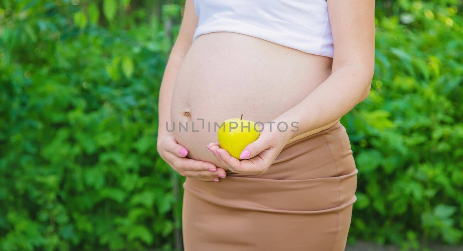 Pregnant woman with an apple in her hands. Selective focus. by yanadjana