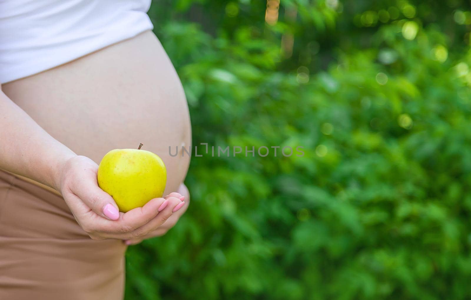 Pregnant woman with an apple in her hands. Selective focus. by yanadjana