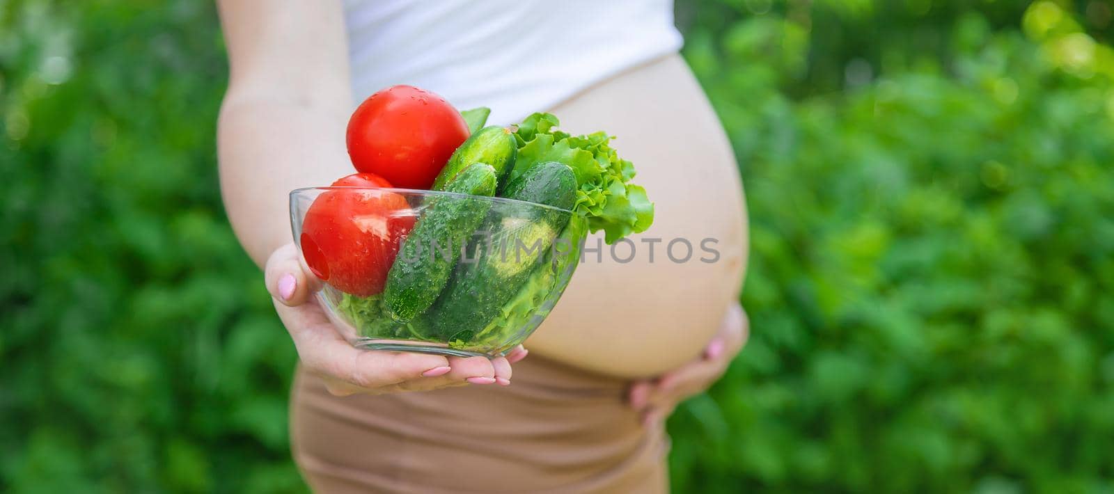 A pregnant woman with vegetables in her hands. Selective focus. food.