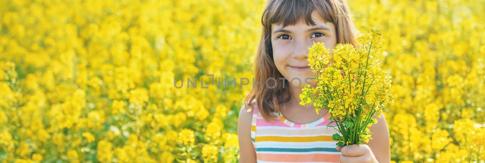 A child in a yellow field, mustard blooms. Selective focus. by yanadjana