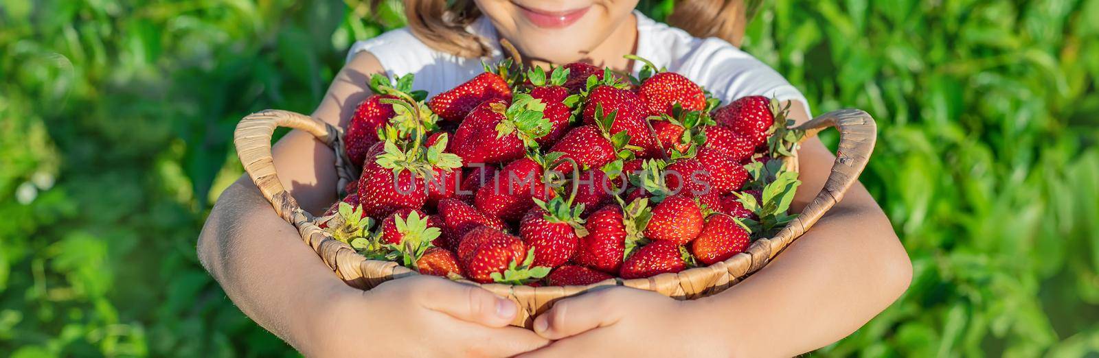 A child with strawberries in the hands. Selective focus. by yanadjana