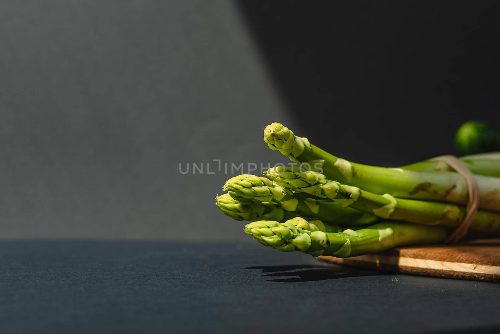 branches of fresh green asparagus on a wooden board, dark gray background, top view. Basic trend concept with copy space