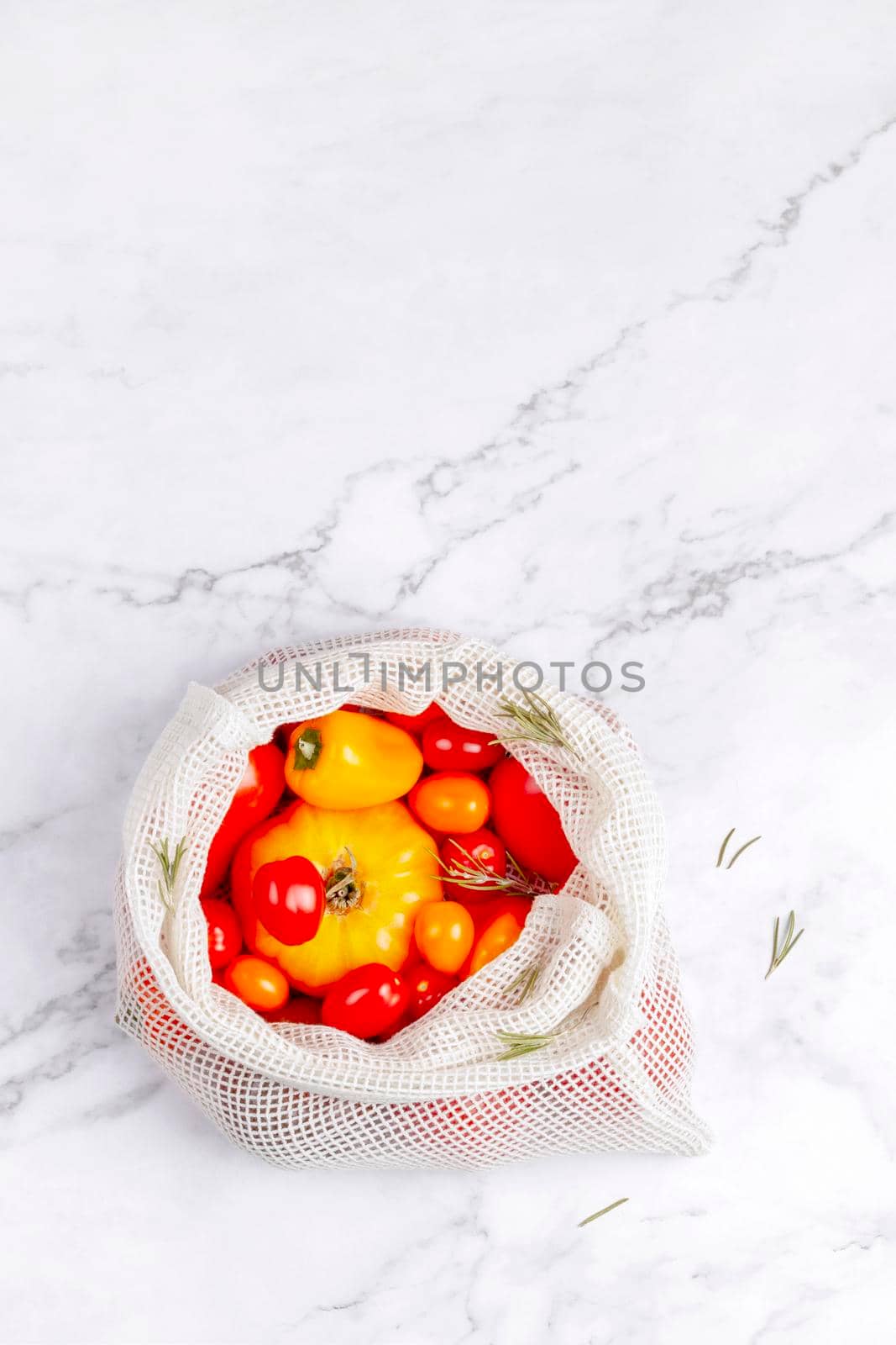 different varieties of tomatoes and bell peppers in a cotton reusable bag, summer vegetables harvest, zero waste concept, top view, copy space