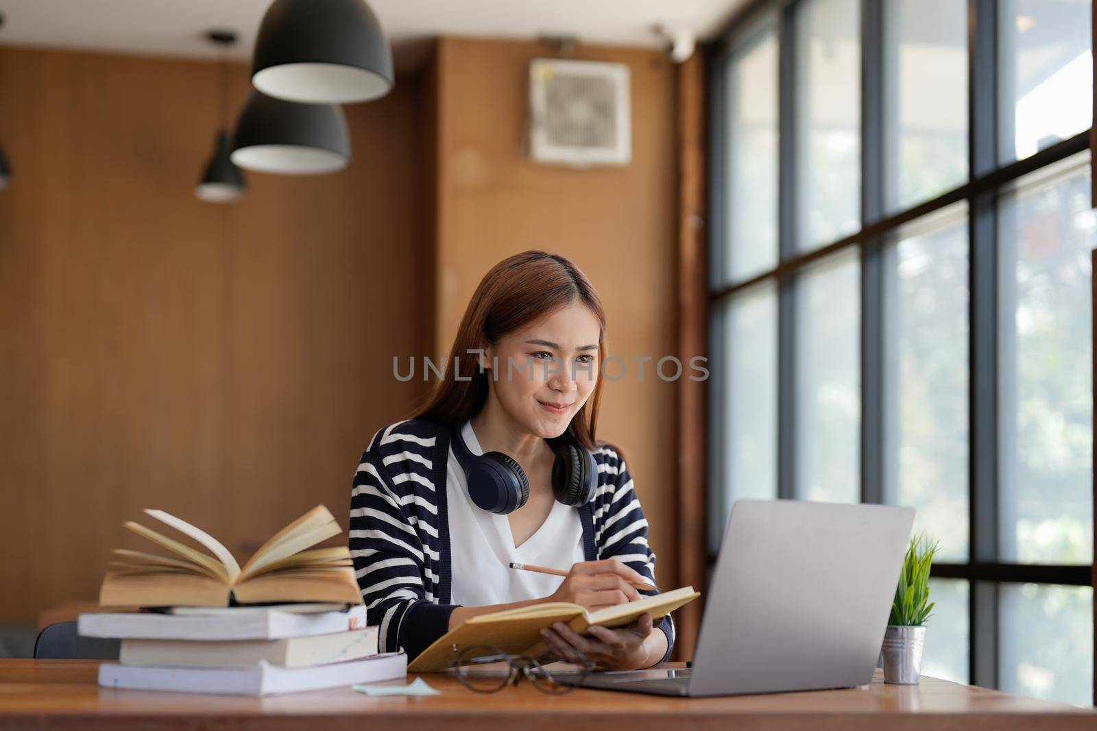 Successful freelancer taking note using laptop computer in at home. Portrait of skilled copywriter at workplace.Smiling student learning languages at library, planning project