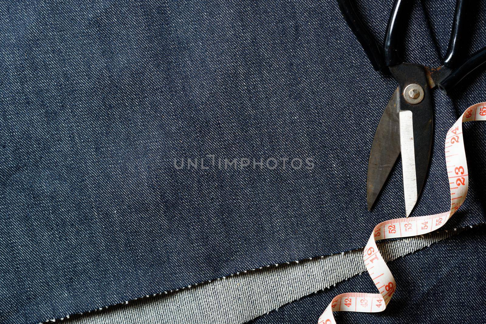 closeup indigo denim fabric texture with dressmaker's tools, material for jeans and other garment.