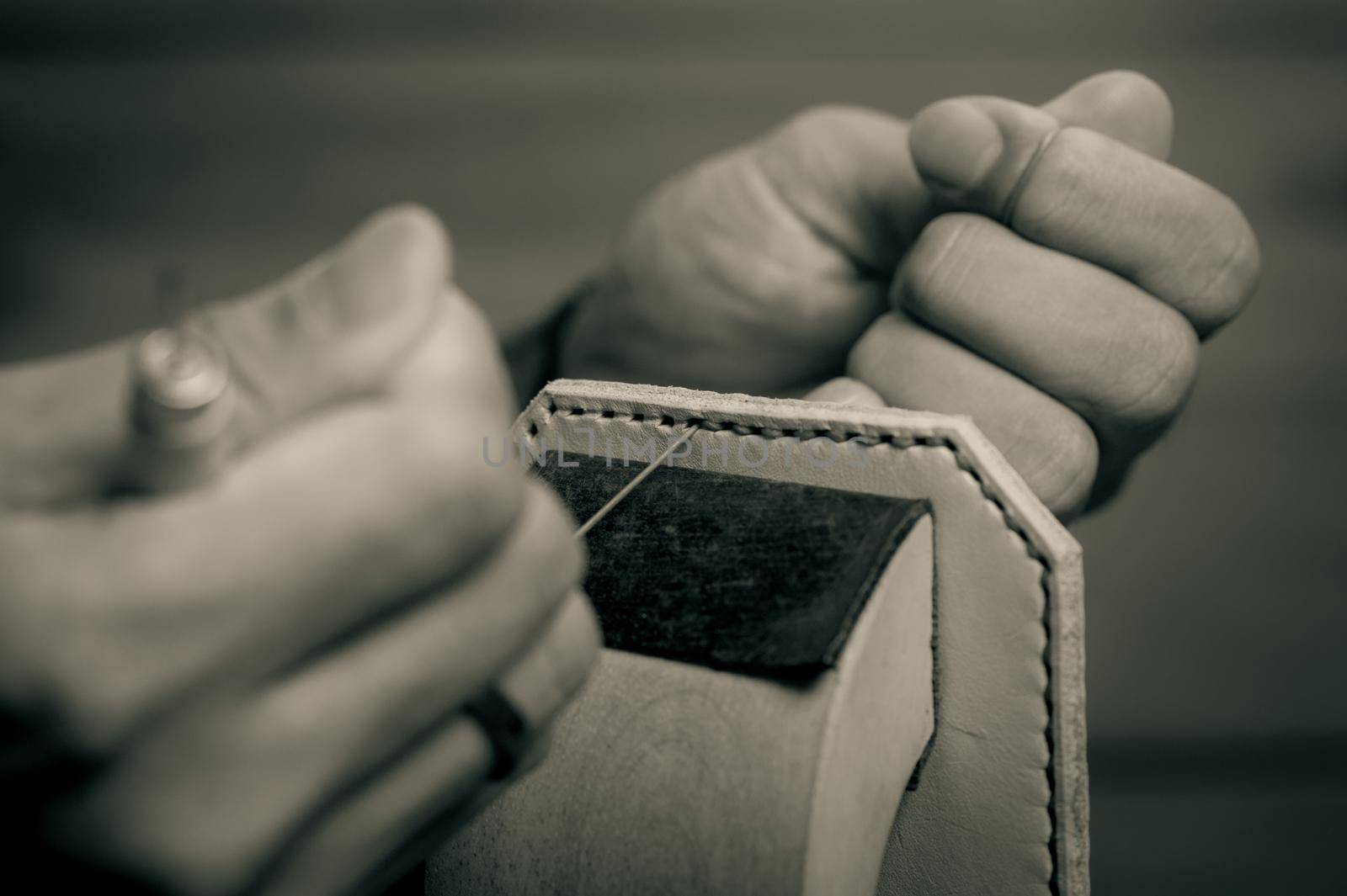 Sewing the vegetable tanned leather by hand. Leather and the craft tools. Monotone and shallow depth of field.
