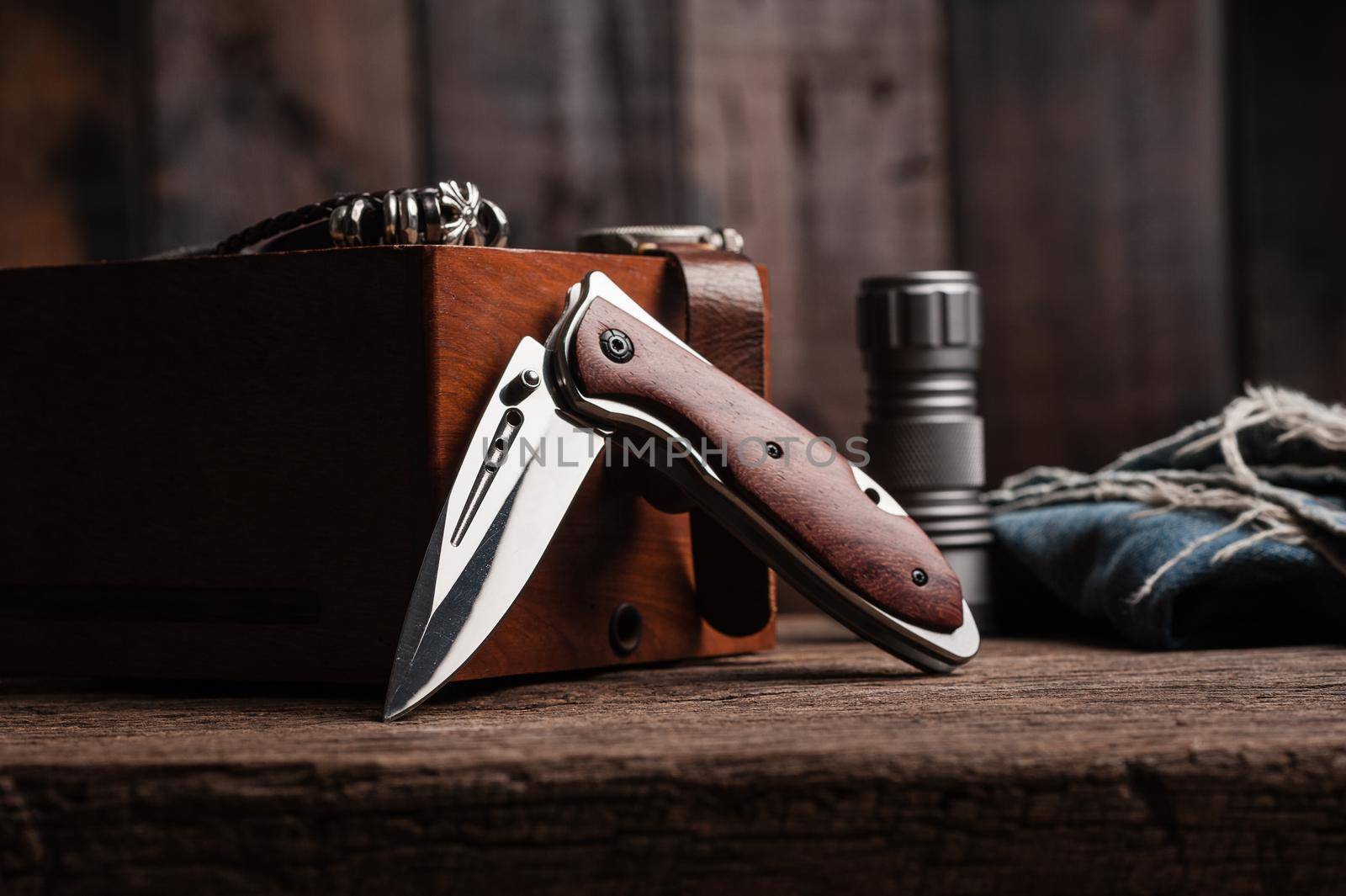 stainless steel folding knife with wooden handle and other everyday carry (EDC) items for men. closeup at folding knife. 