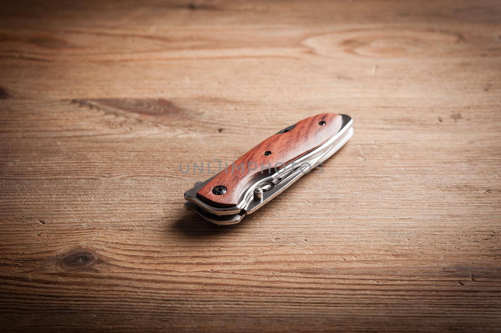 stainless steel folding knife isolated over wood background