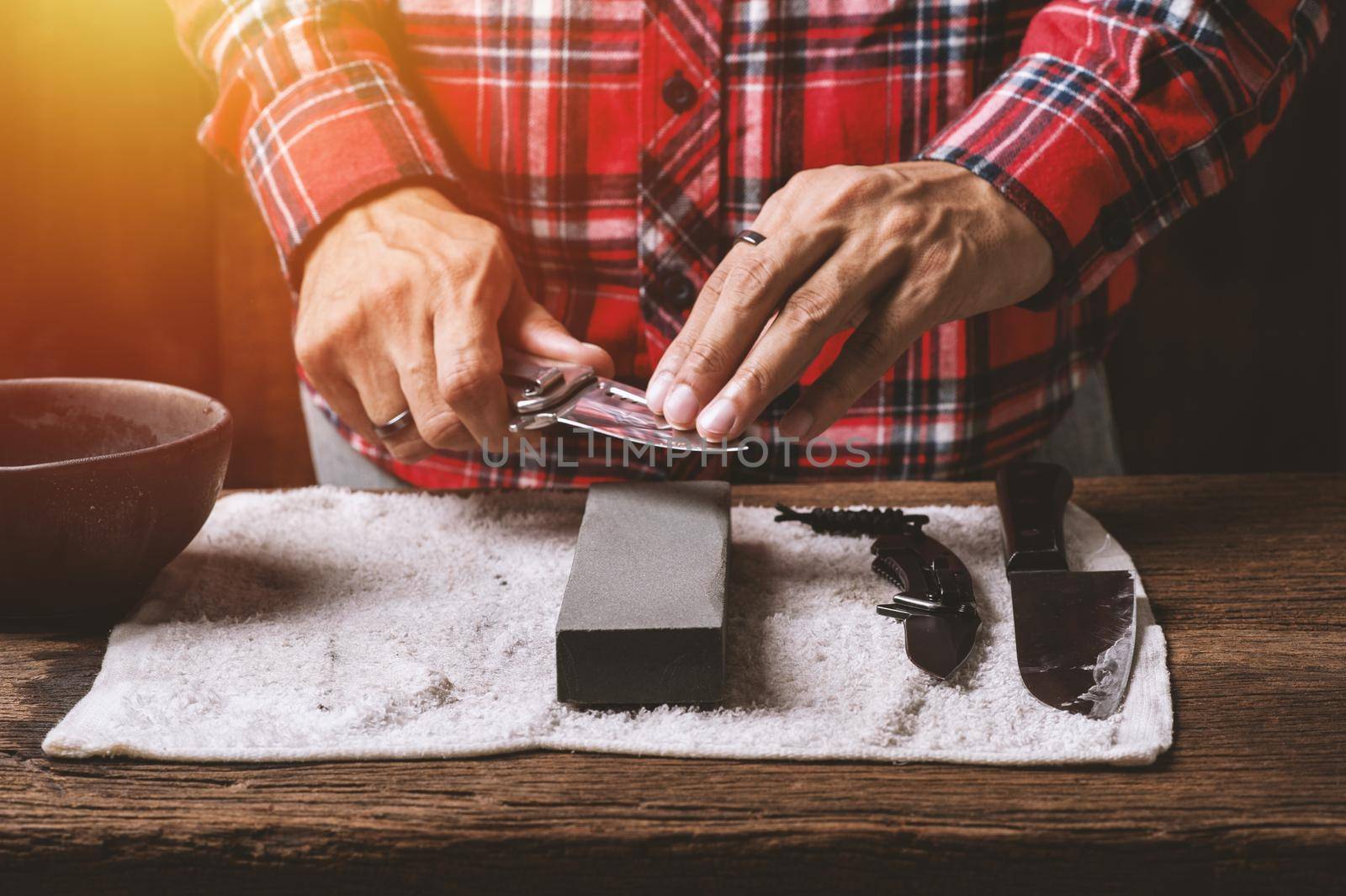 The man using whetstone to sharpening his pocket knife. Pocket knife care and maintenance concept.