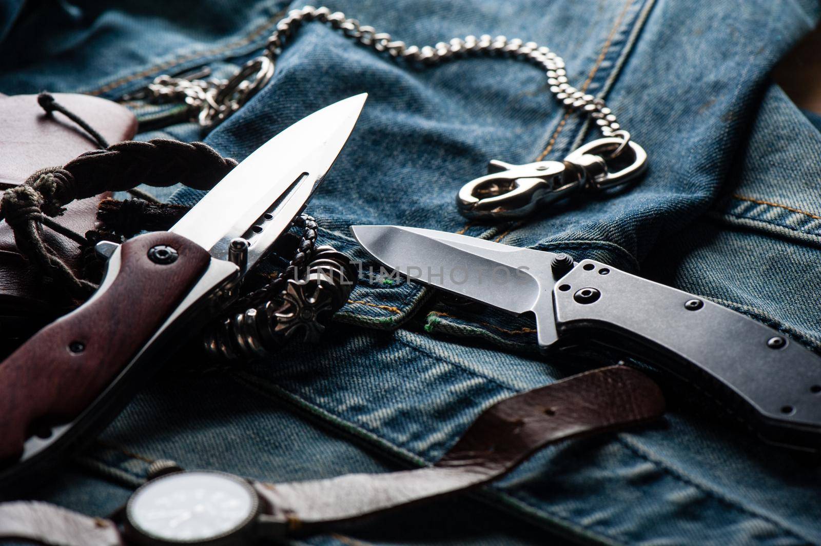 stainless steel folding knife with wooden handle and other everyday carry (EDC) items for men. closeup at folding knife. (low light and shallow depth of field)