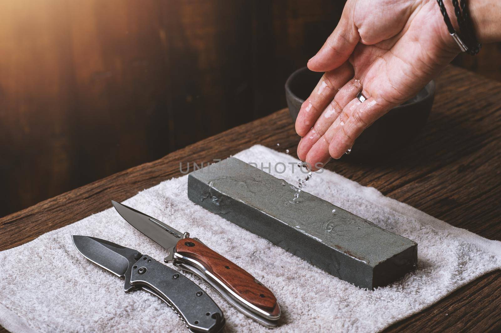 The man using whetstone to sharpening his pocket knife. Pocket knife care and maintenance concept.