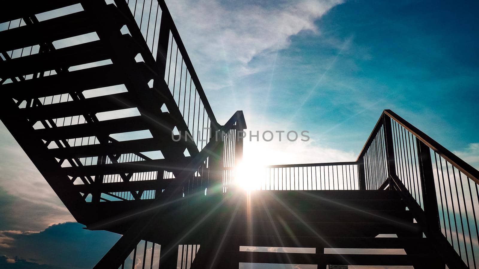 Outdoor iron staircase black color steel structure architecture construction over sunlight with beautiful blue sky background by Petrichor