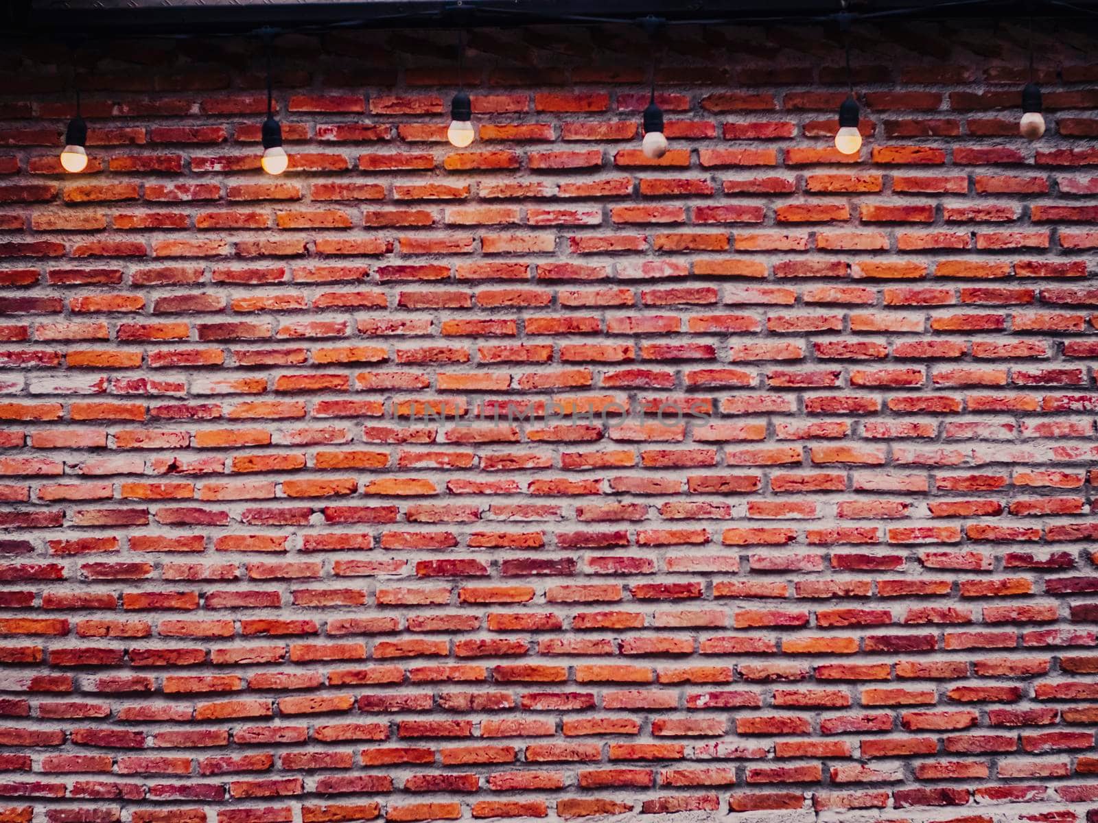 Red brick wall with bulbs vintage and retro background.  Red Brick Empty Wall with Light Bulbs Background. Industrial loft style of decoration.