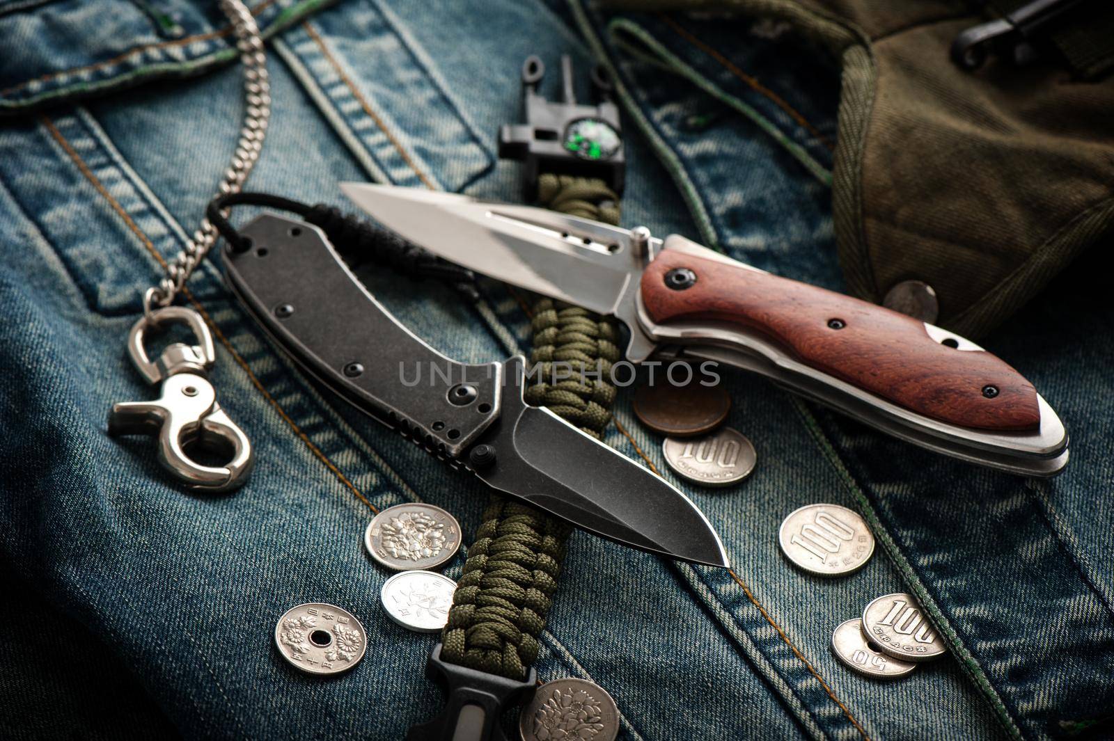 stainless steel folding knife and other everyday carry (EDC) items for men. closeup at folding knife. (low light and shallow depth of field)