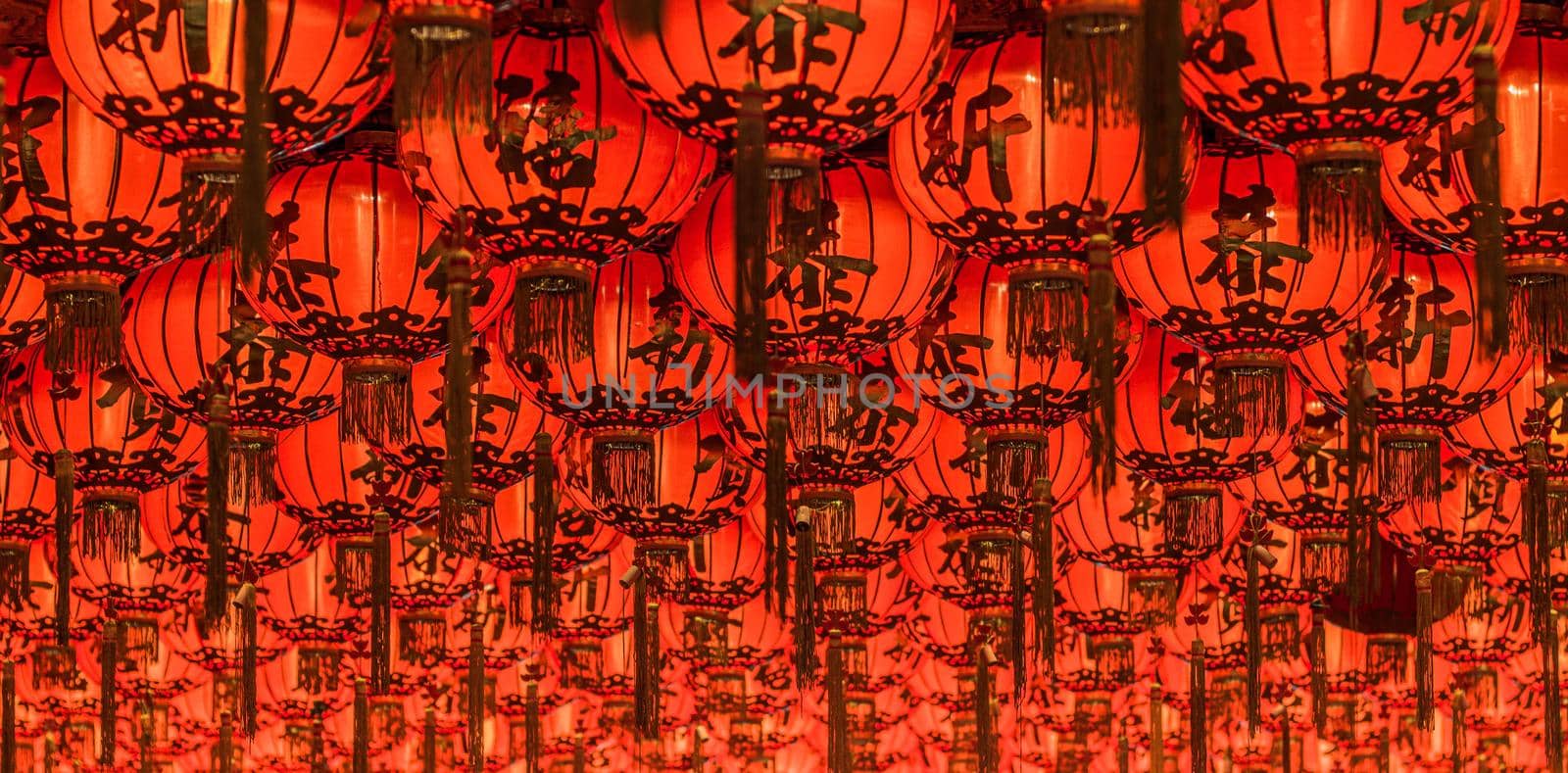 Chinese red lanterns hanging in street at night for decoration. Chinese letter written mean good luck. by Petrichor