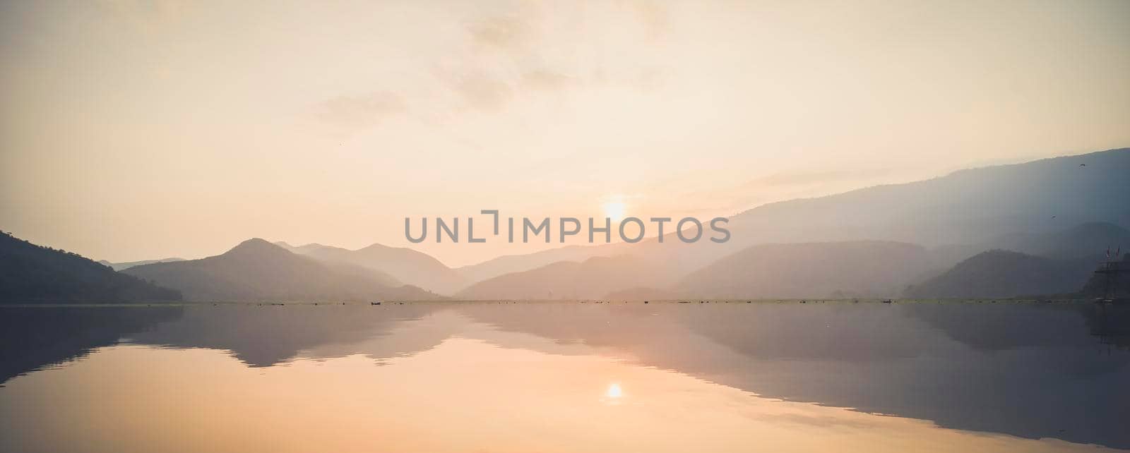 Mountain, sky and river in a quiet and cool atmosphere. Similar color scheme .View of blue mountains with reflection in lake . Landscape with blue mountains near lake in Sukhothai Thailand