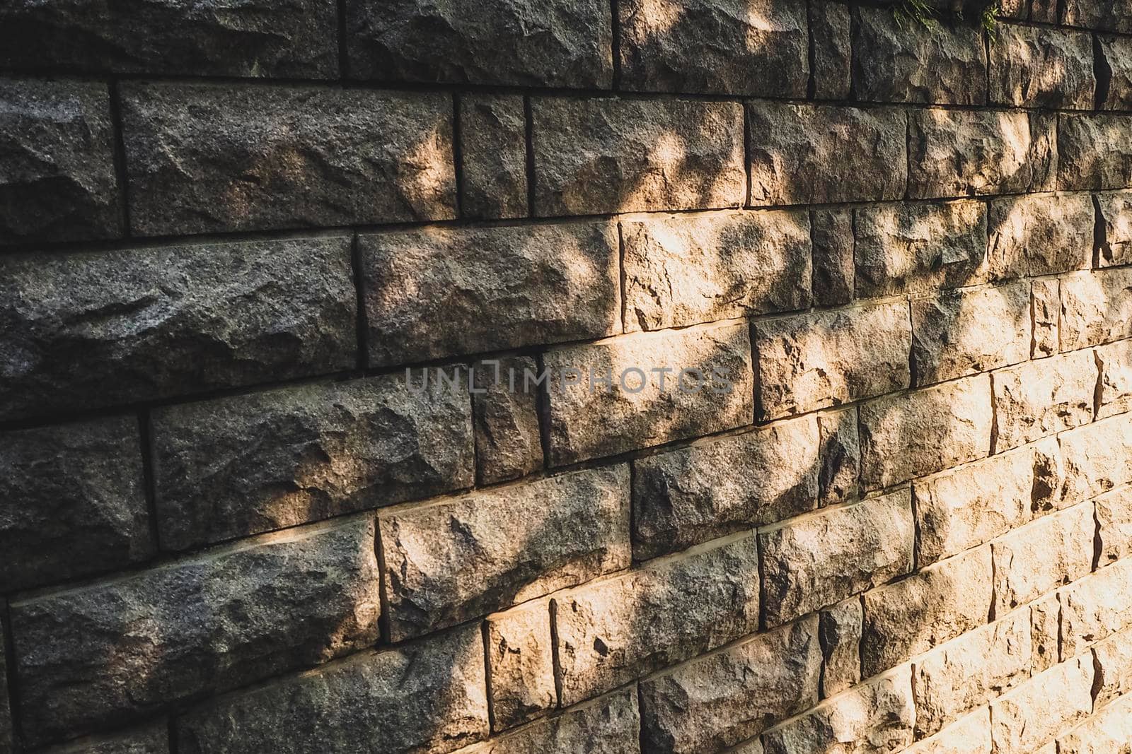 Background stone wall with patches of sunlight, light and shadow, solar hares, stone wall sun