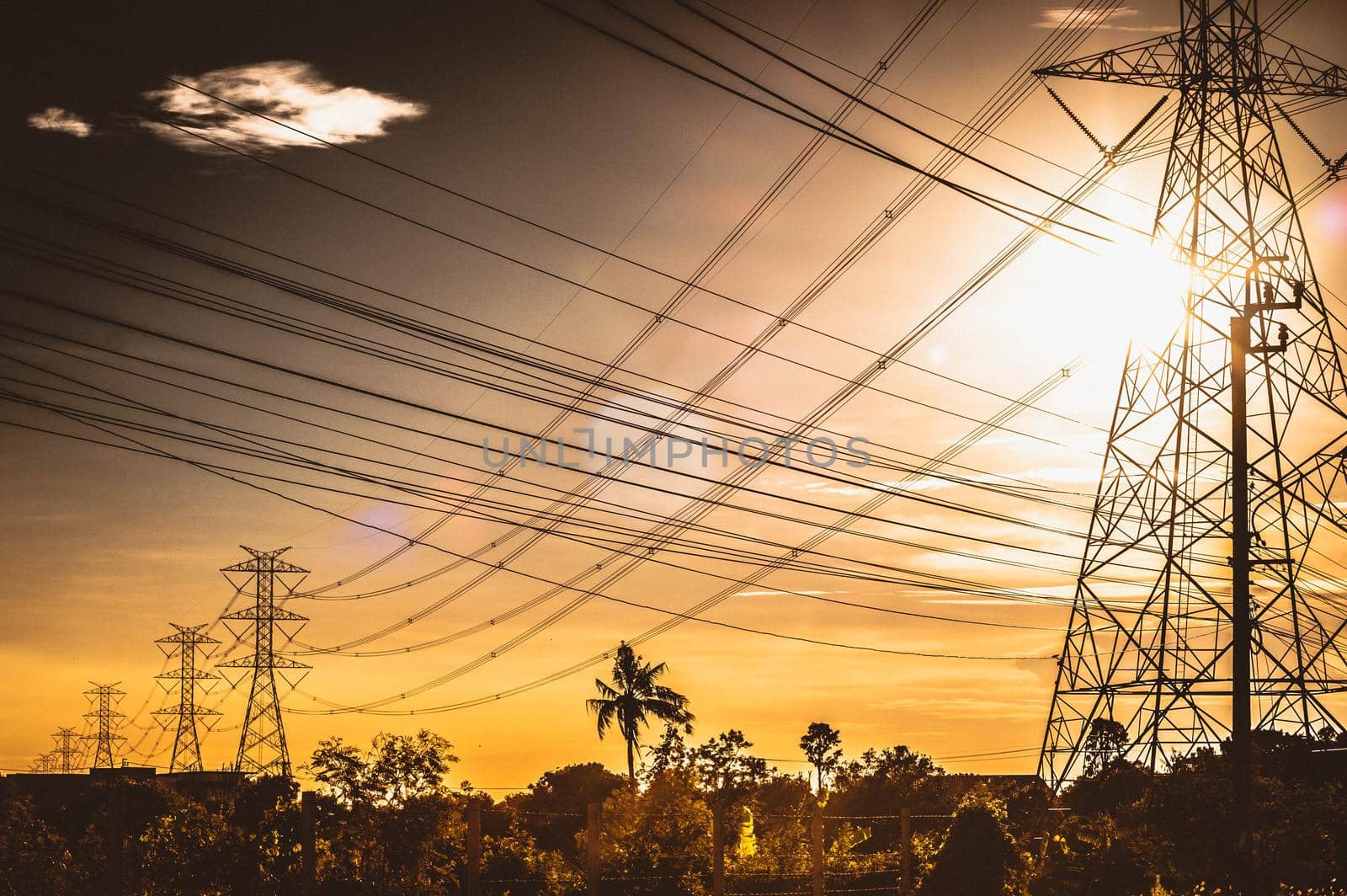 Electric power line plant station tower pole in the field on sunset background. Abstract energy power.