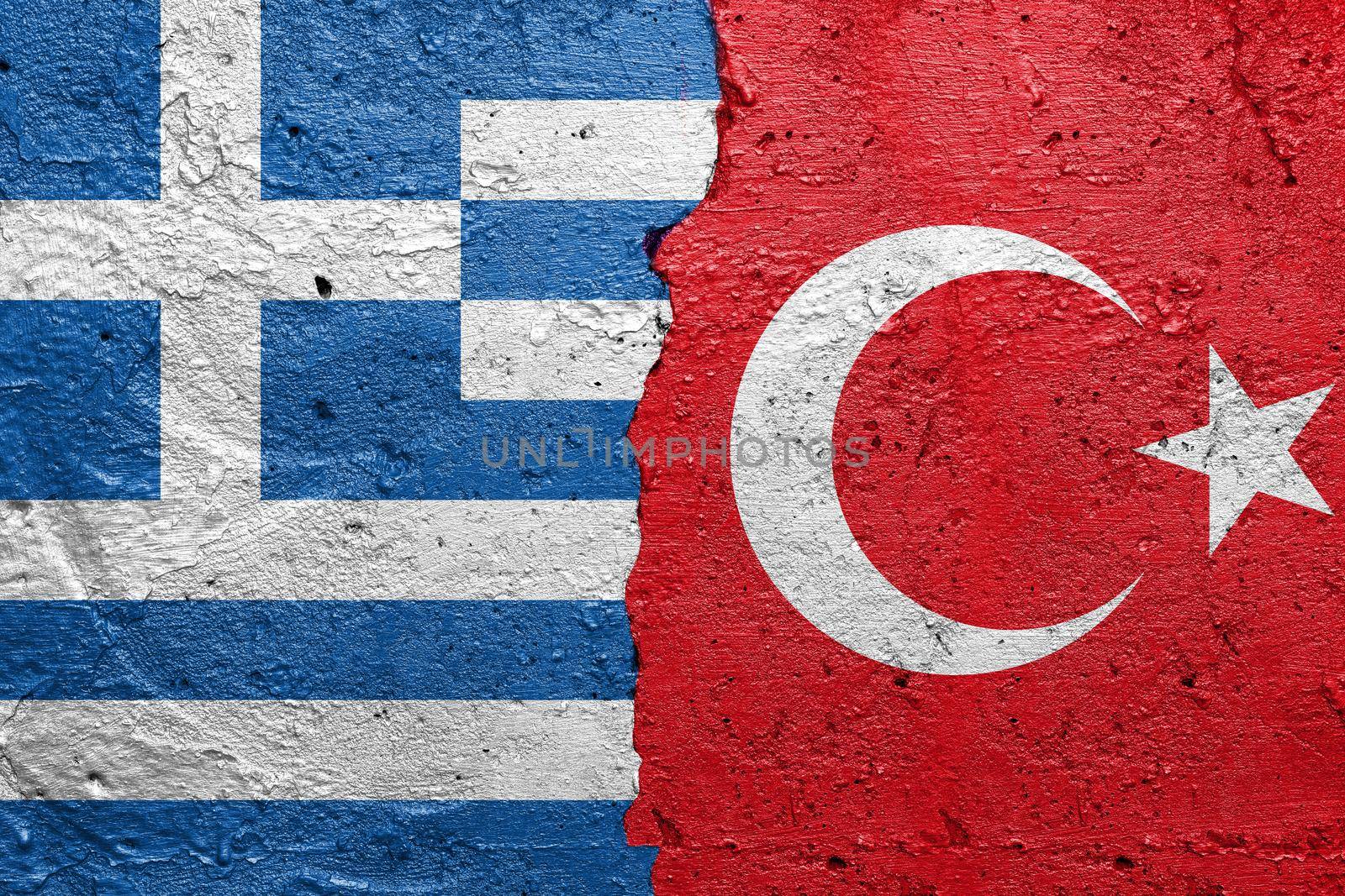 Greece and Turkey- Cracked concrete wall painted with a Greek flag on the left and a Turkish flag on the right stock photo by adamr