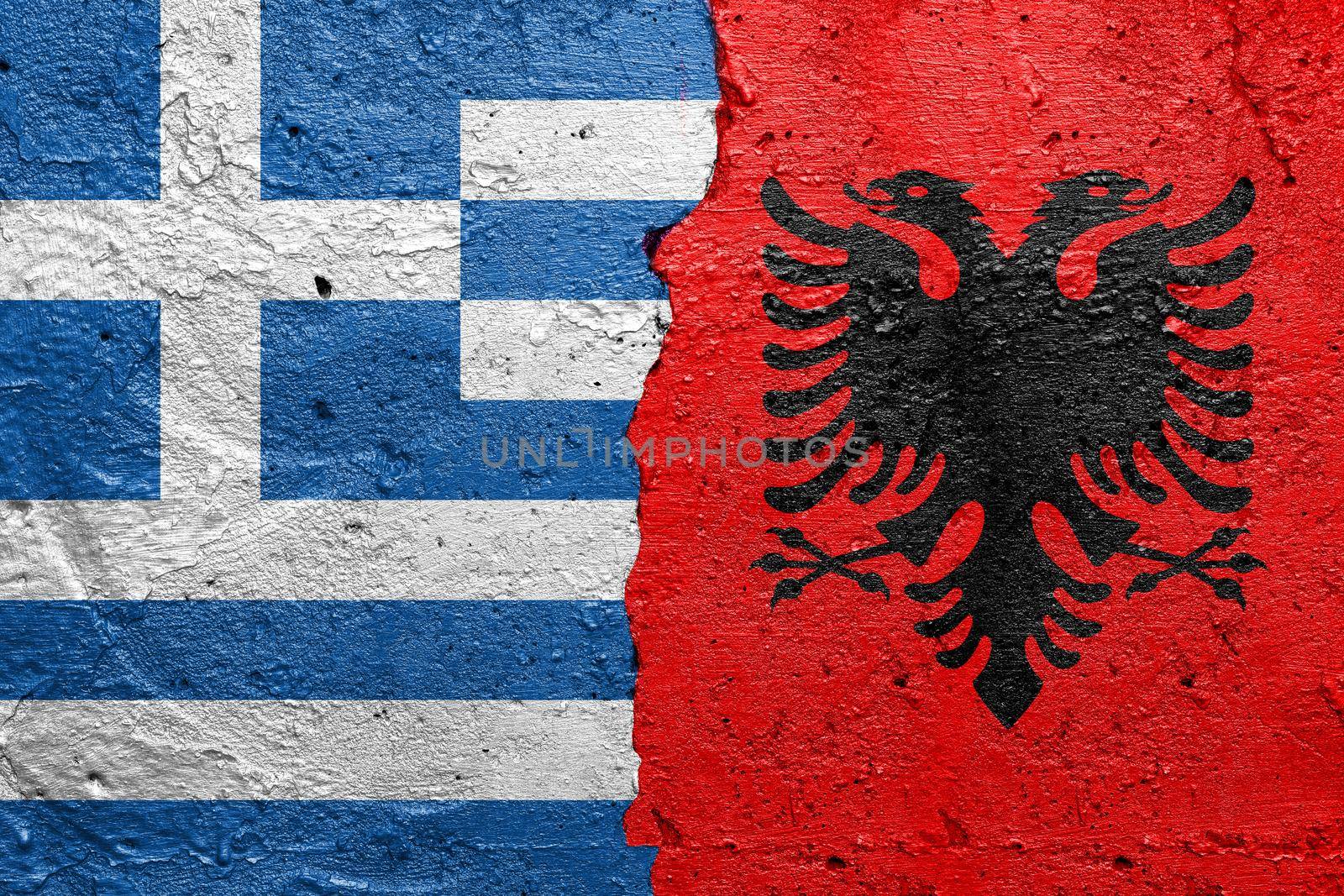 Greece and Albania- Cracked concrete wall painted with a Greek flag on the left and a Albanian flag on the right stock photo by adamr