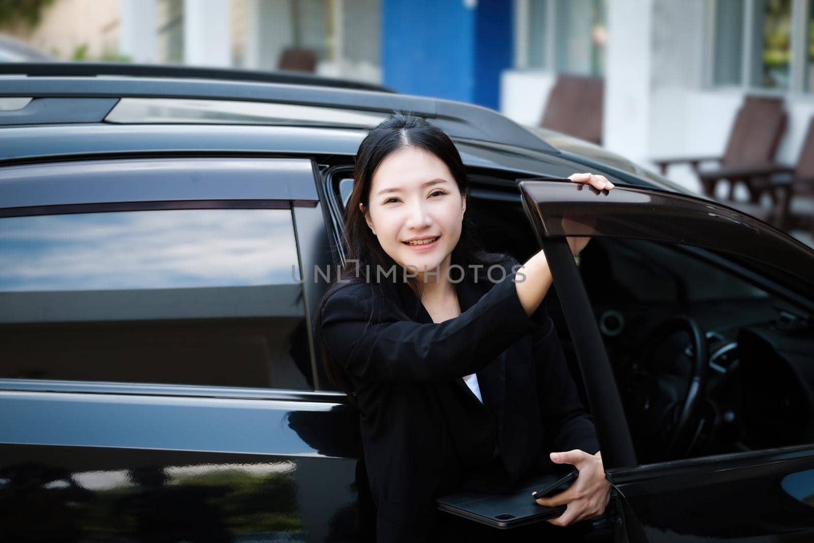 Asian businessmen, business owners, company presidents or female employees holding smartphone mobile and a tablet are getting out of the car to attend a business plan meeting at the meeting. by Manastrong