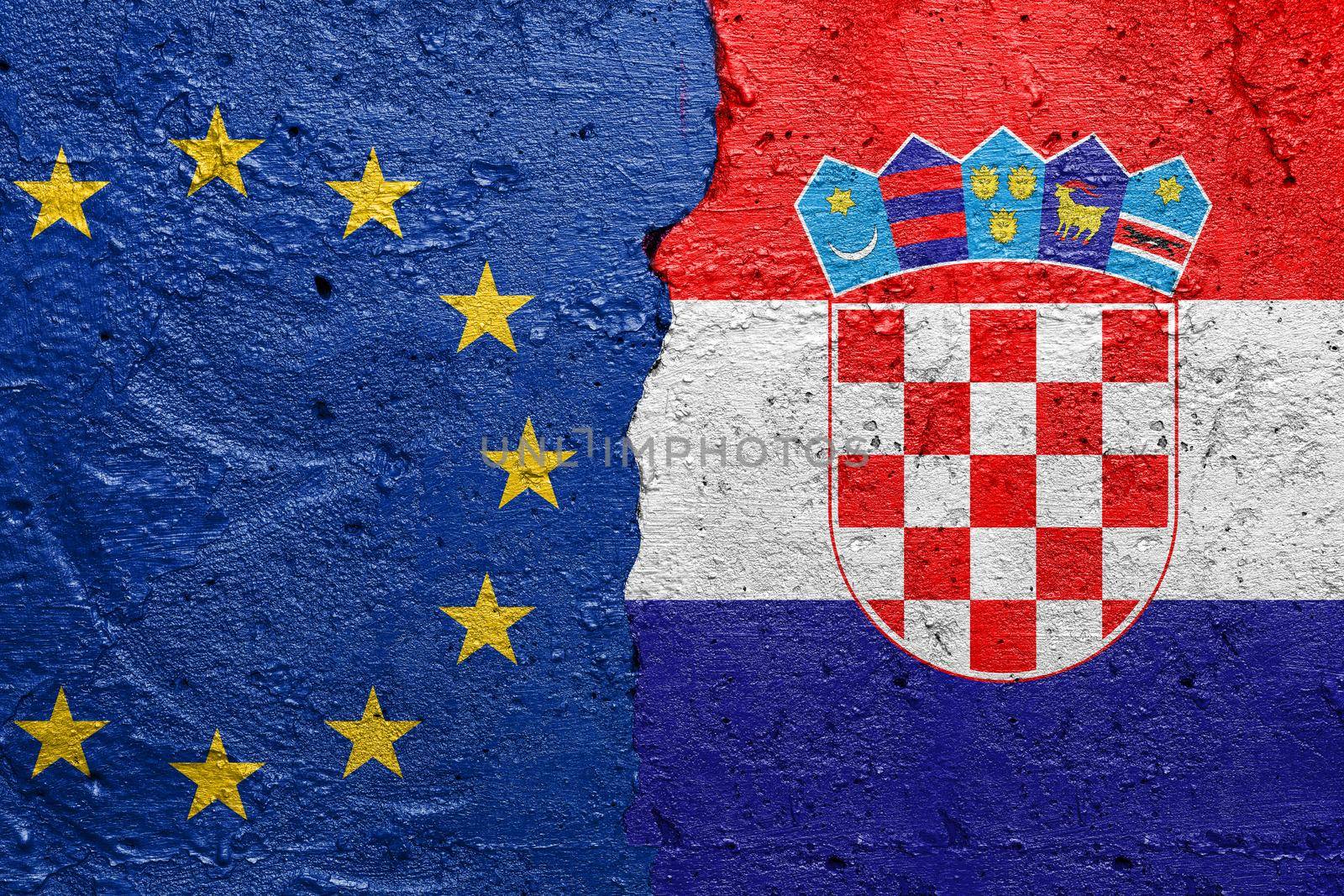 European Union EU and Croatia - Cracked concrete wall painted with a EU flag on the left and a Croatian flag on the right stock photo by adamr