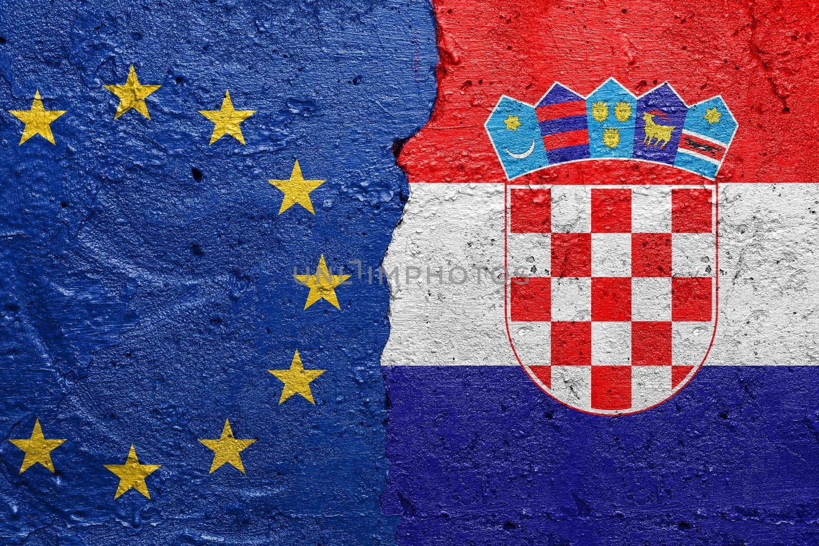 European Union EU and Croatia - Cracked concrete wall painted with a EU flag on the left and a Croatian flag on the right