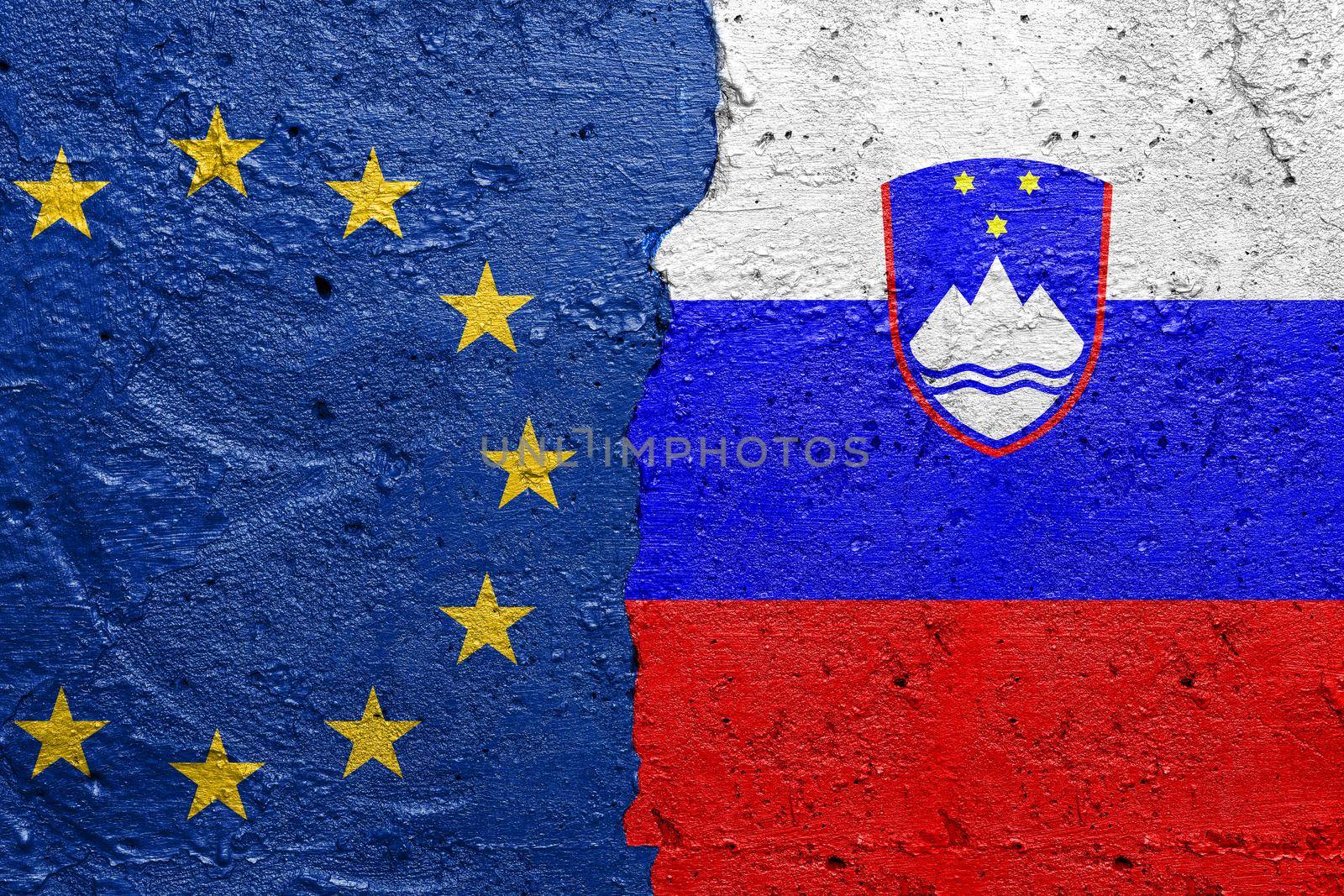 European Union EU and Slovenia - Cracked concrete wall painted with a EU flag on the left and a Slovanian flag on the right stock photo by adamr