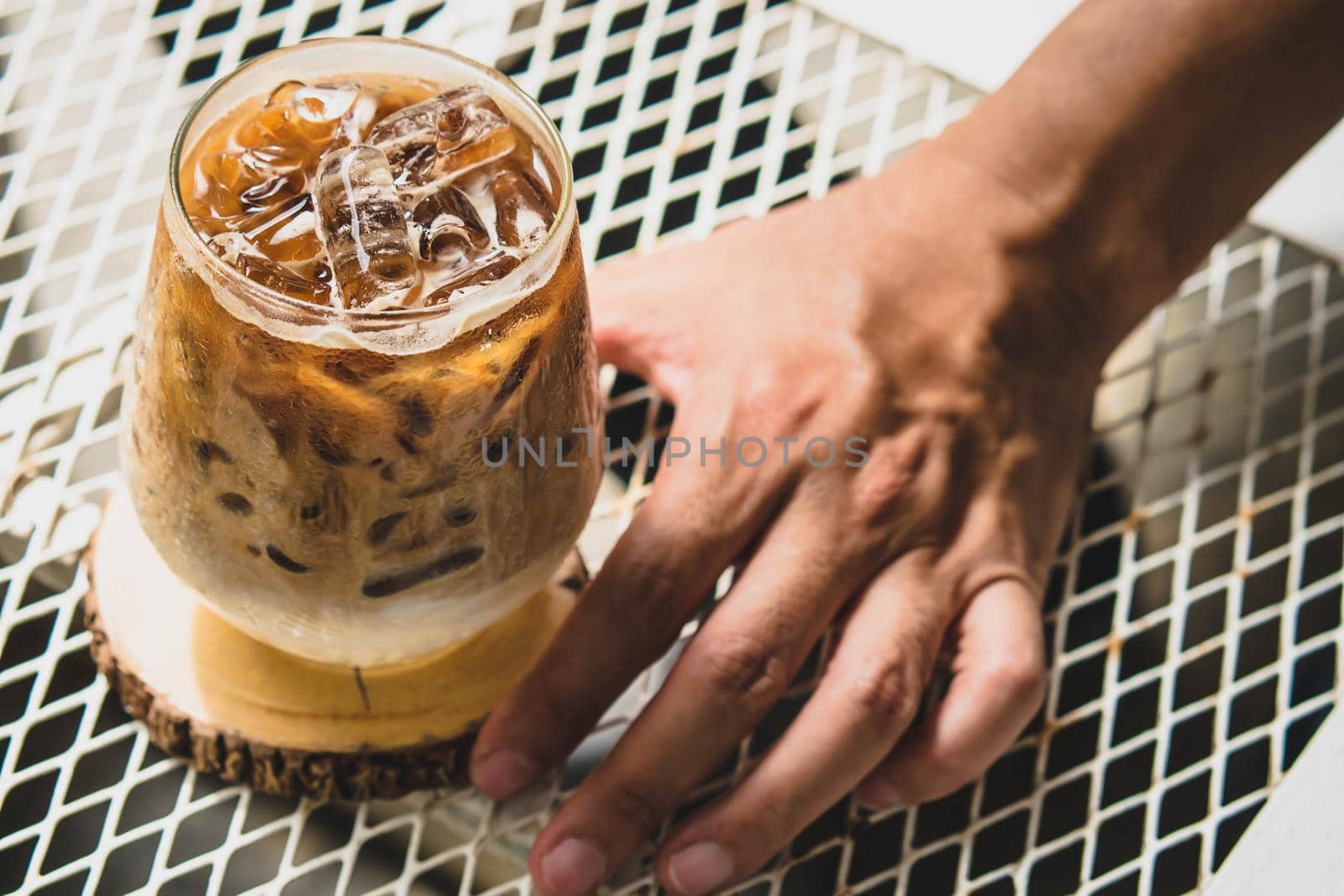 Selective focus Man hold cup of iced coffee. Glass of Cold Coffee with Milk on Table for summertime, selective focus.