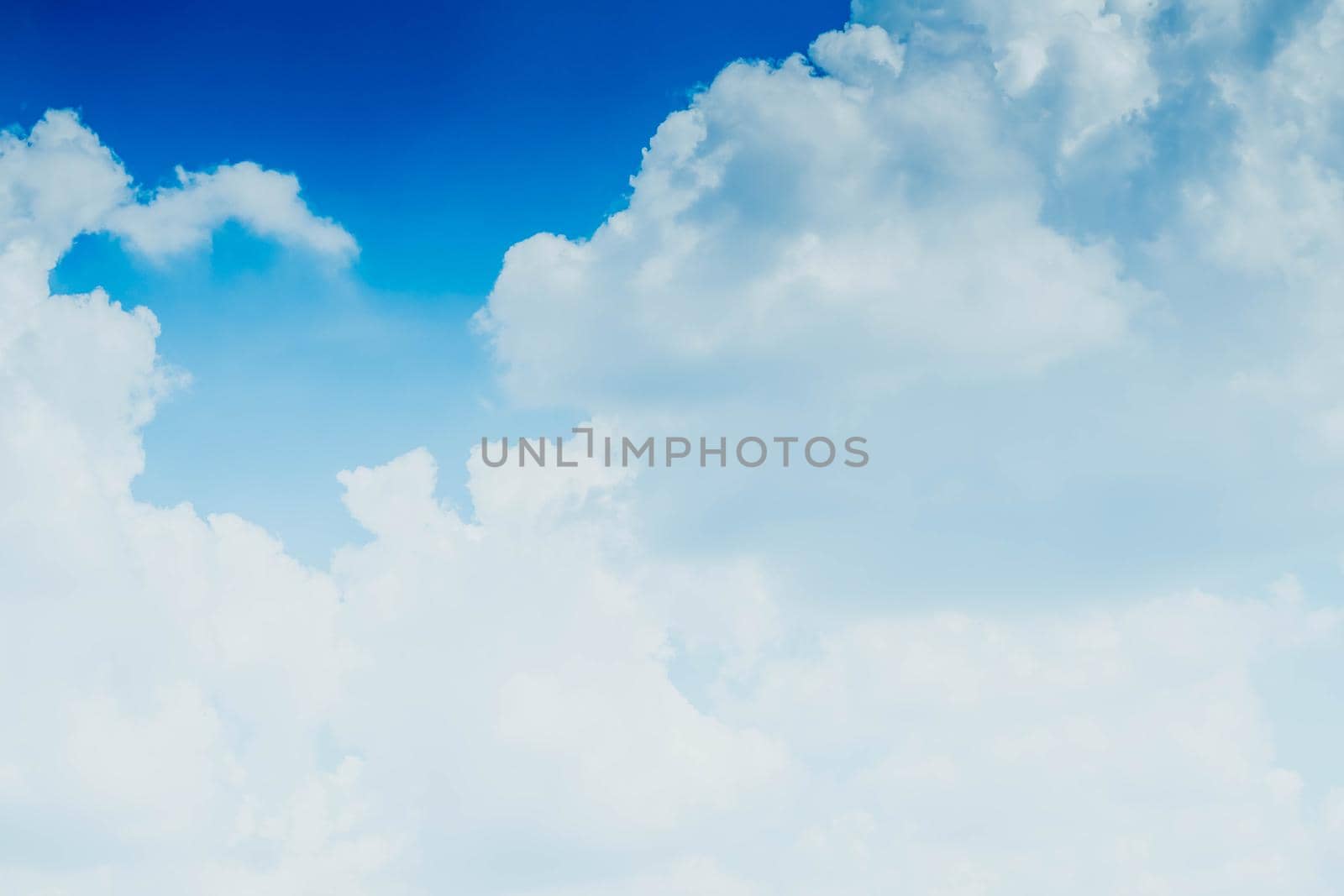 White fluffy clouds against blue sky in summer nature season weather background by Petrichor