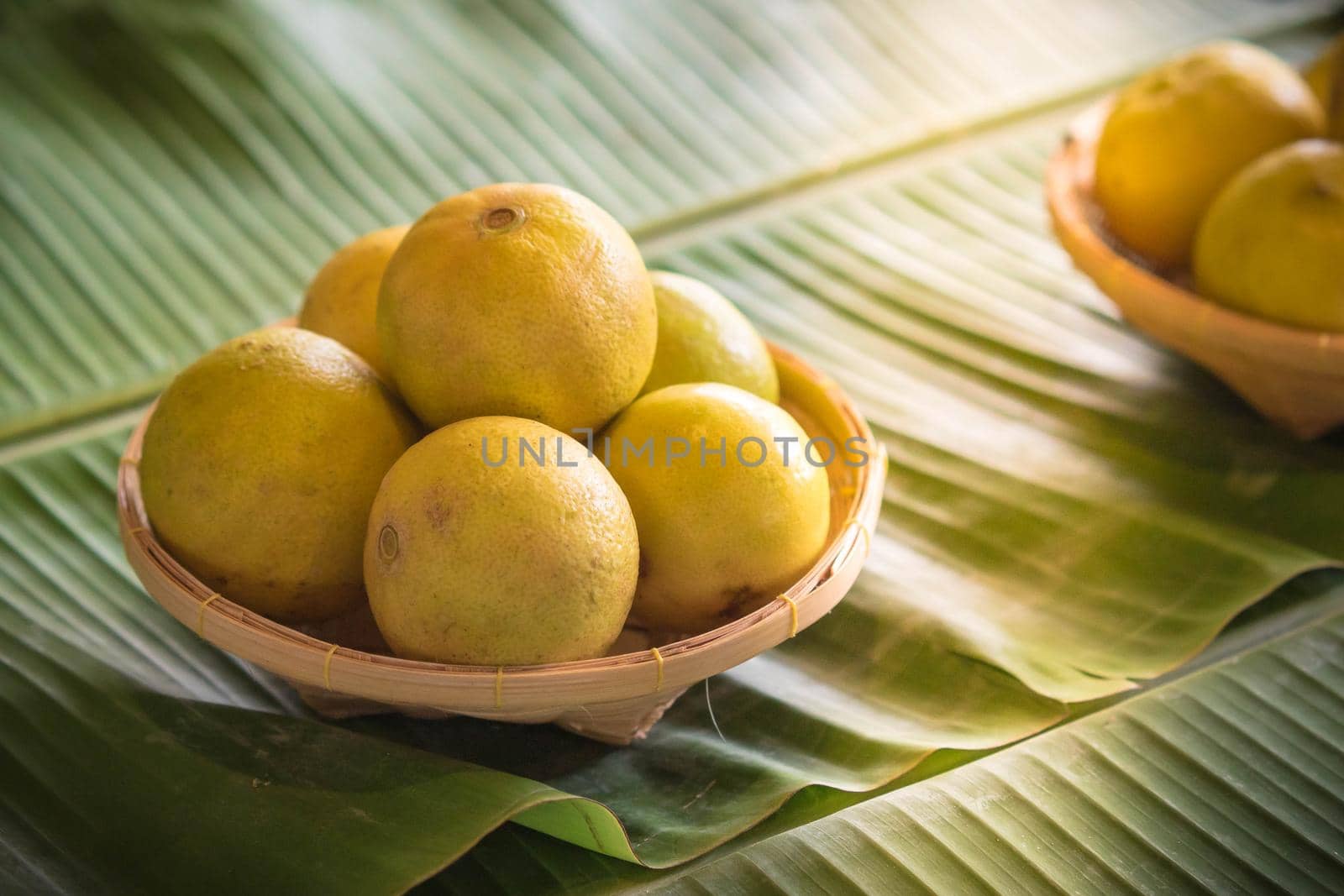 Lemons in basket weave on green banana leaf. Healthy fruits background