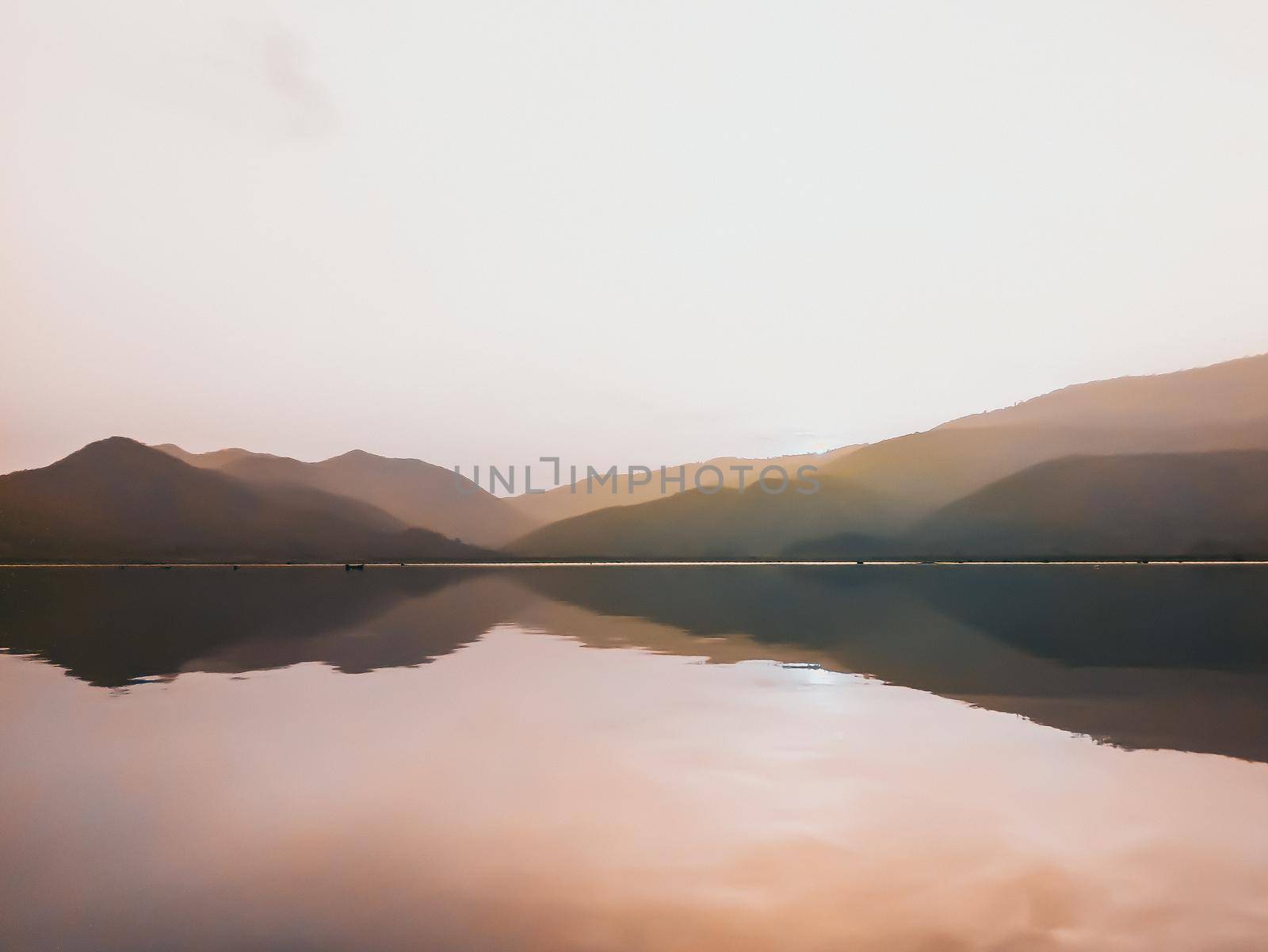 Panorama scenic of beautiful sunset at the lake with mountain ranges on background. Minimal nature.