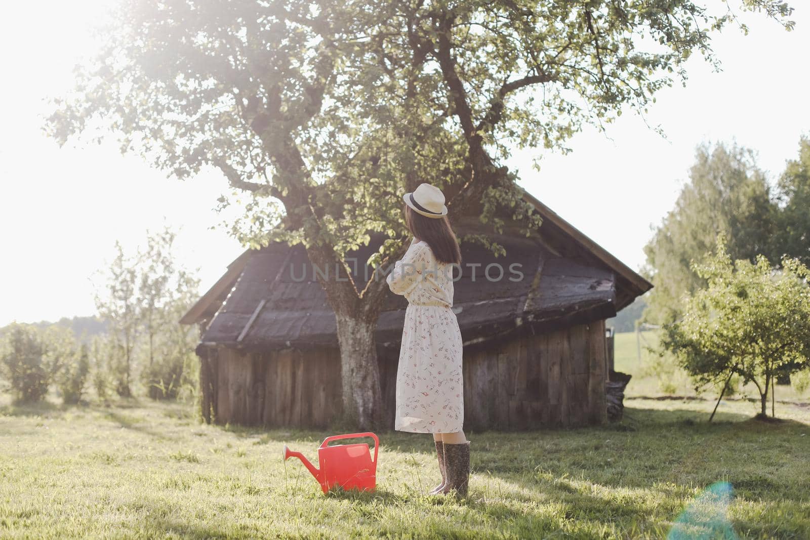 Young female gardener watering the plants in the garden in summer. Young woman with a watering can.