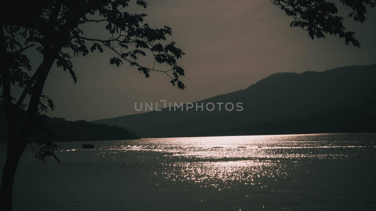 light reflection by surface waves of a lake at sunset with mountain background.