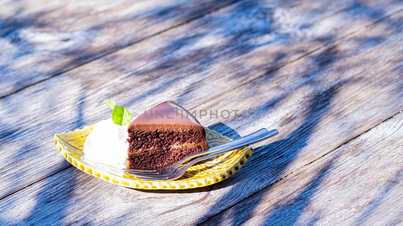 chocolate fudge cake serve with cream on vintage wooden table.
