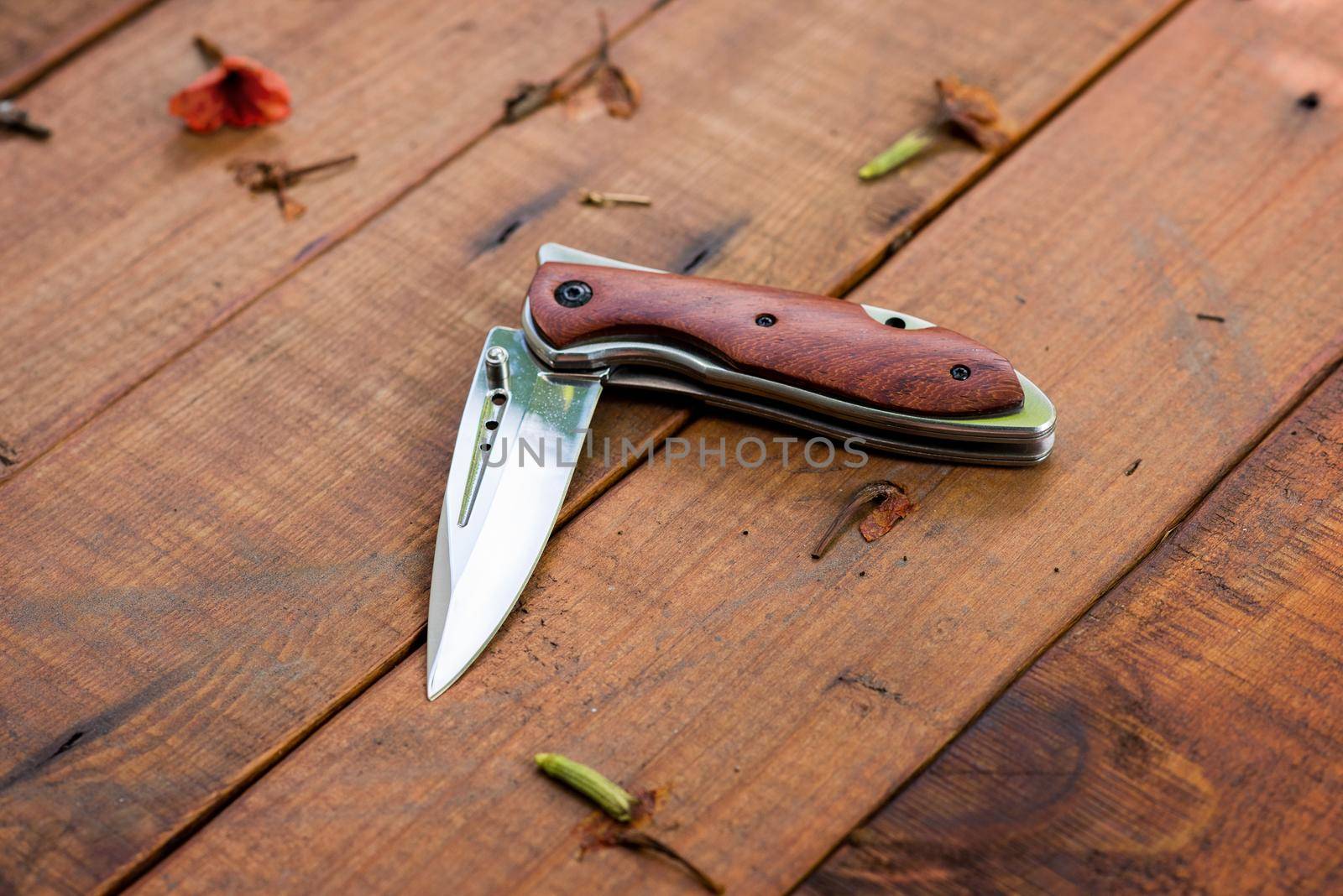 stainless steel folding knife isolated over wood background