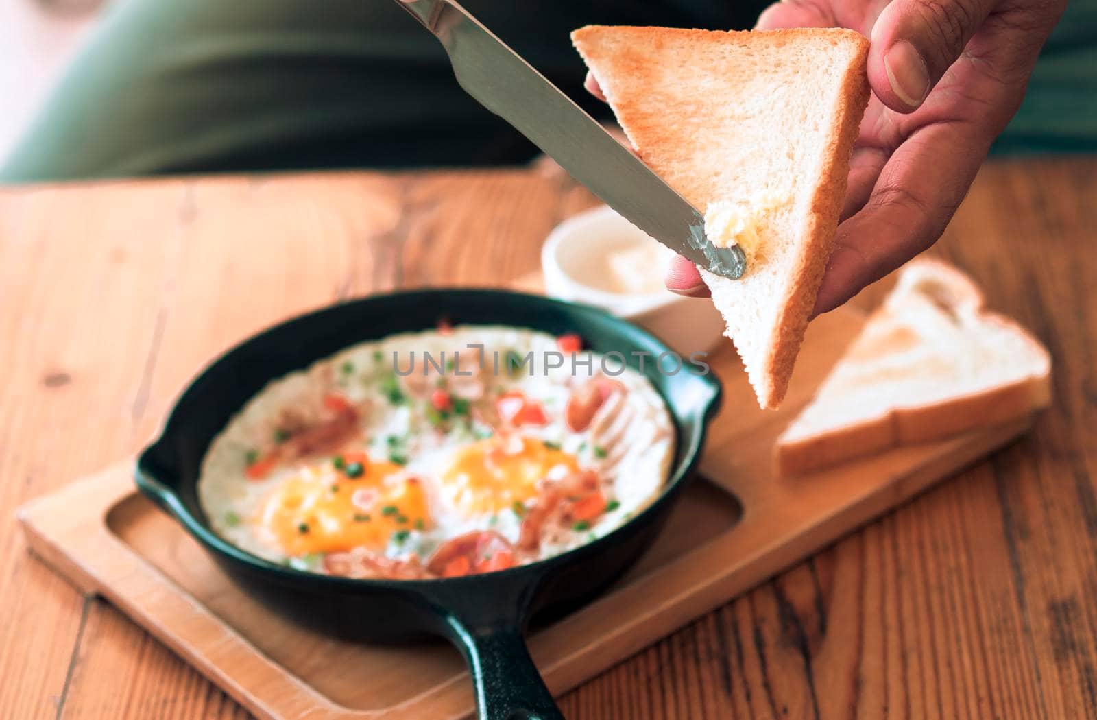 Man spreading butter on the bread with Pan Fried Egg with Toppings