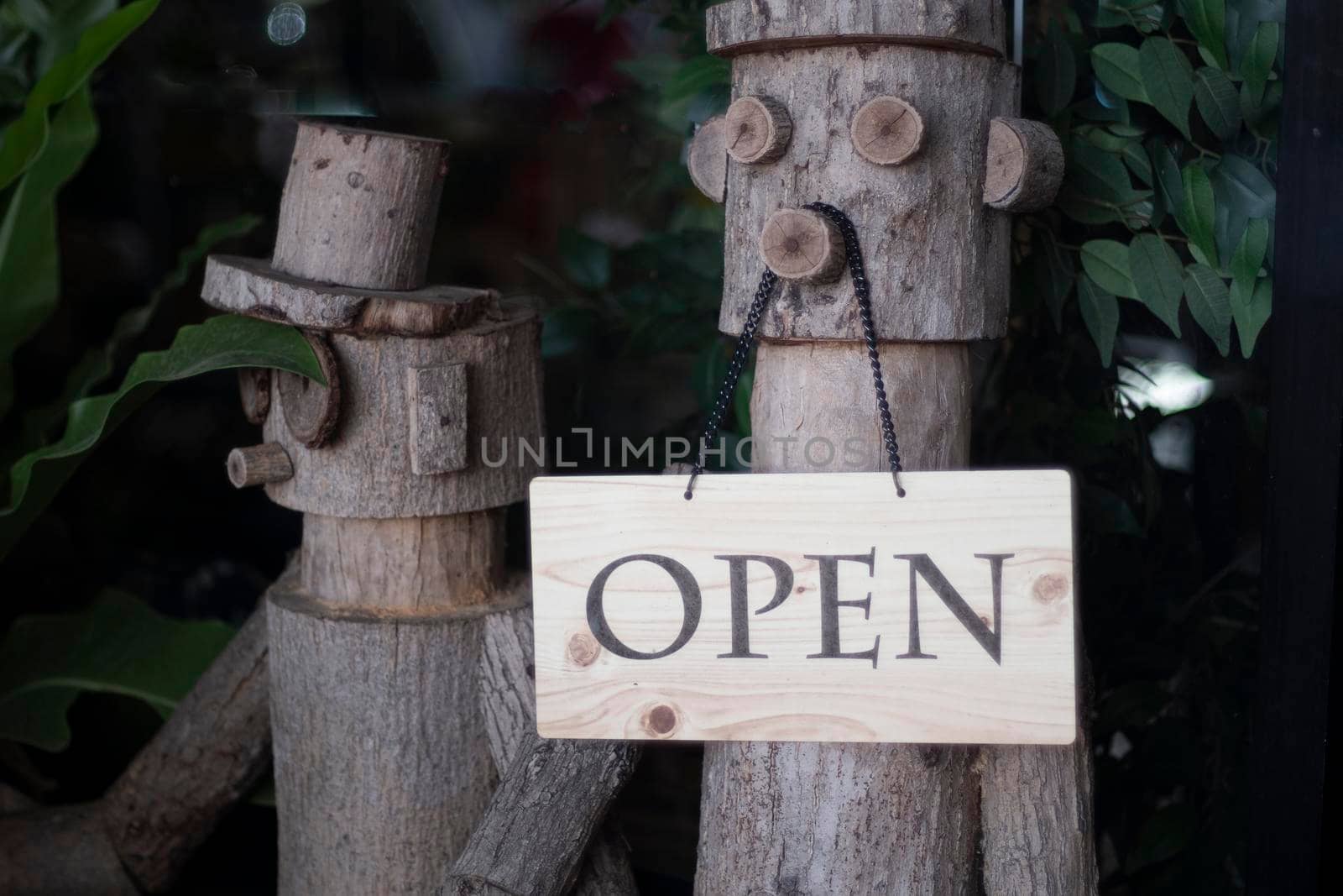 Open Sign Hanging on wooden doll in front of entrance door for decoration cafe restuarant. by Petrichor