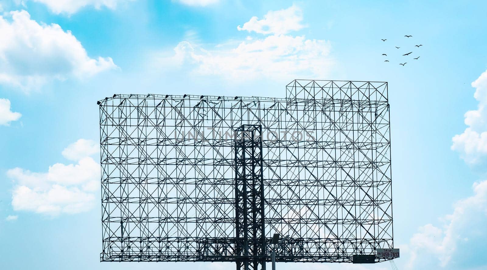 Empty advertising billboard steel truss structure against cloud blue sky