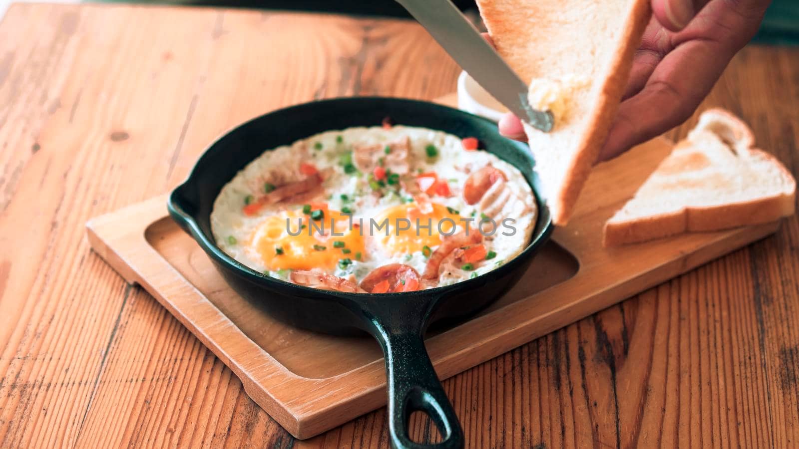 Man spreading butter on the bread with Pan Fried Egg with Toppings