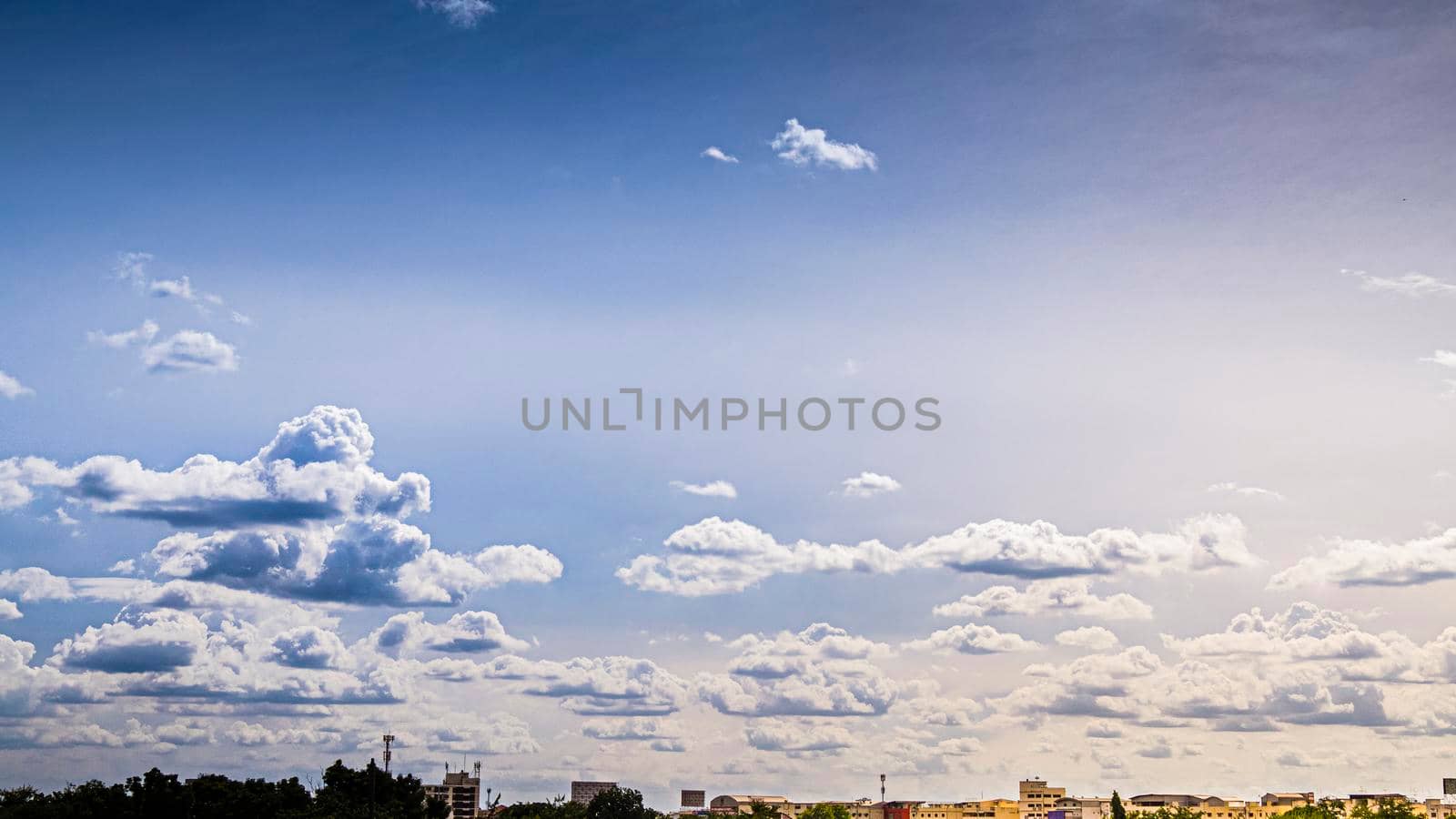 Panoramic view of city background blue sky with white huge single floating clouds against blue sky