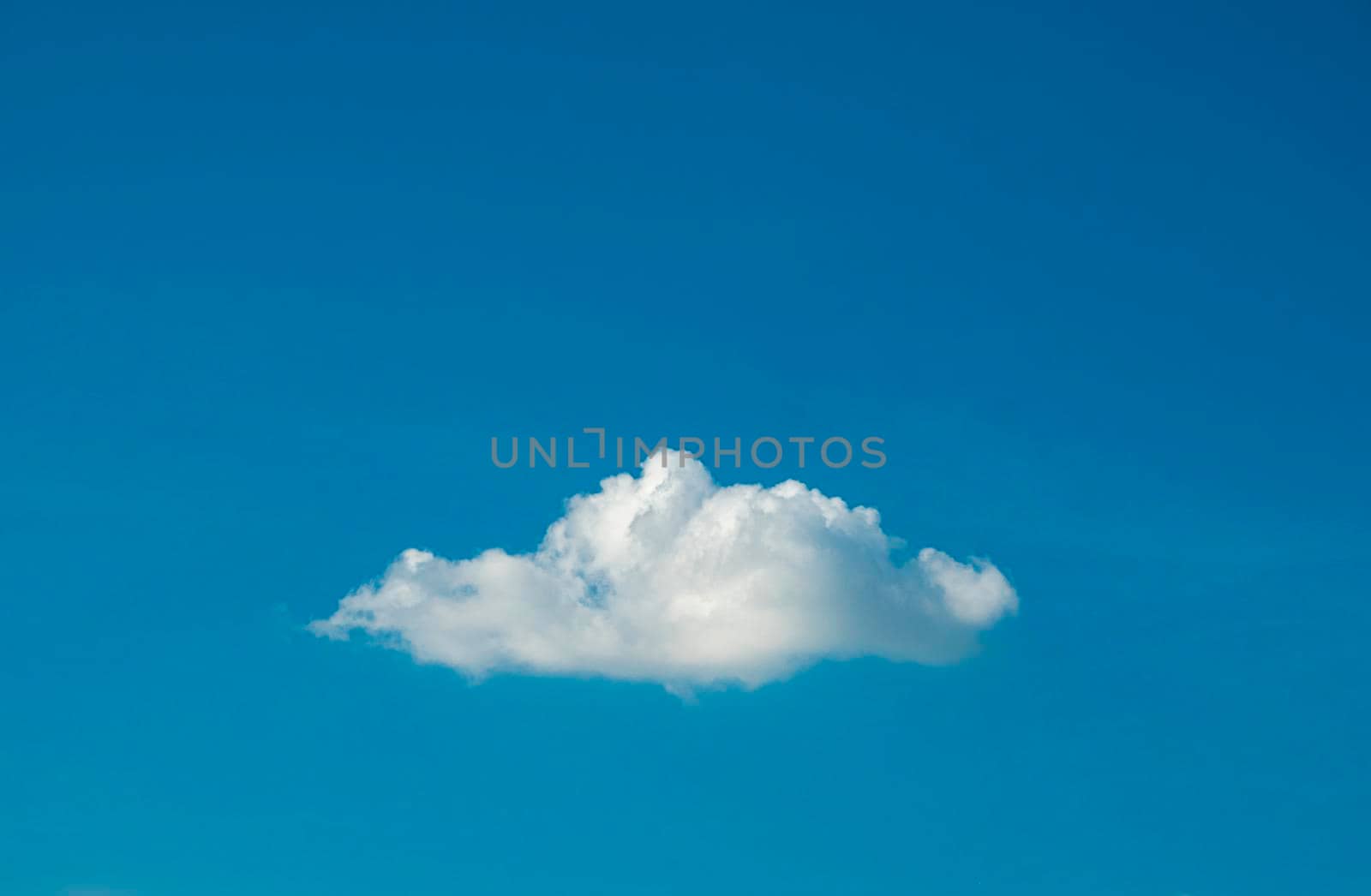 Cute white fluffy single cloud on clear blue sky background.