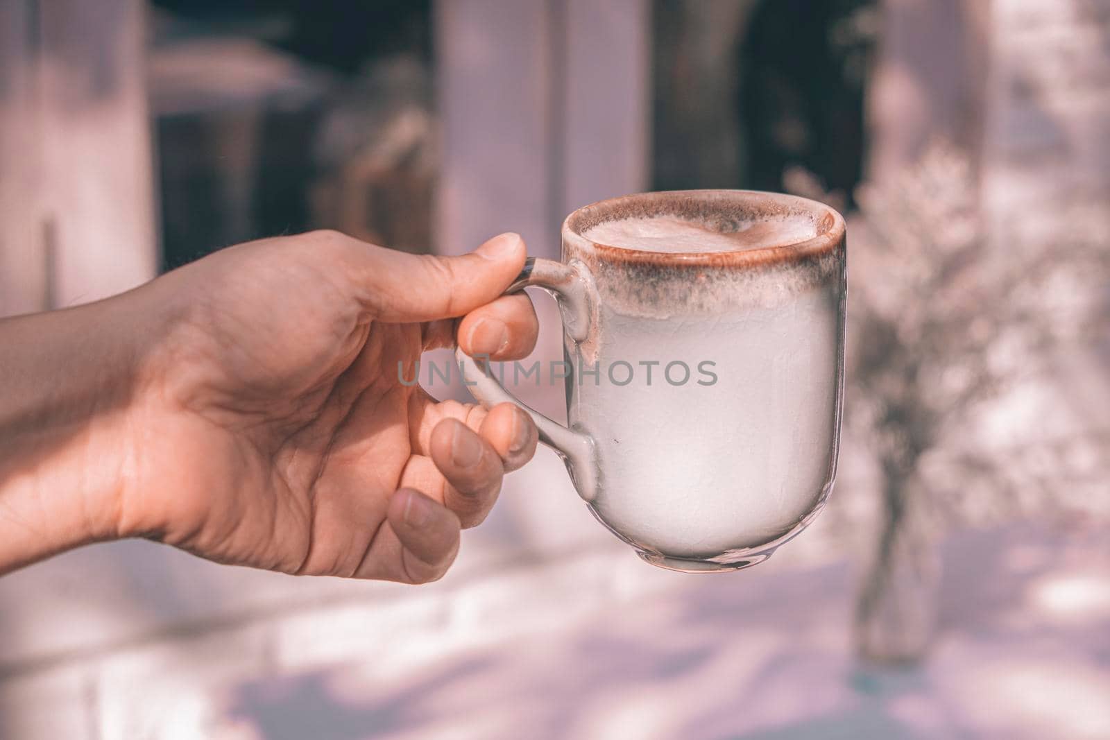 Hands of a man or barista holding cup of hot coffee latte with heart shaped foam art