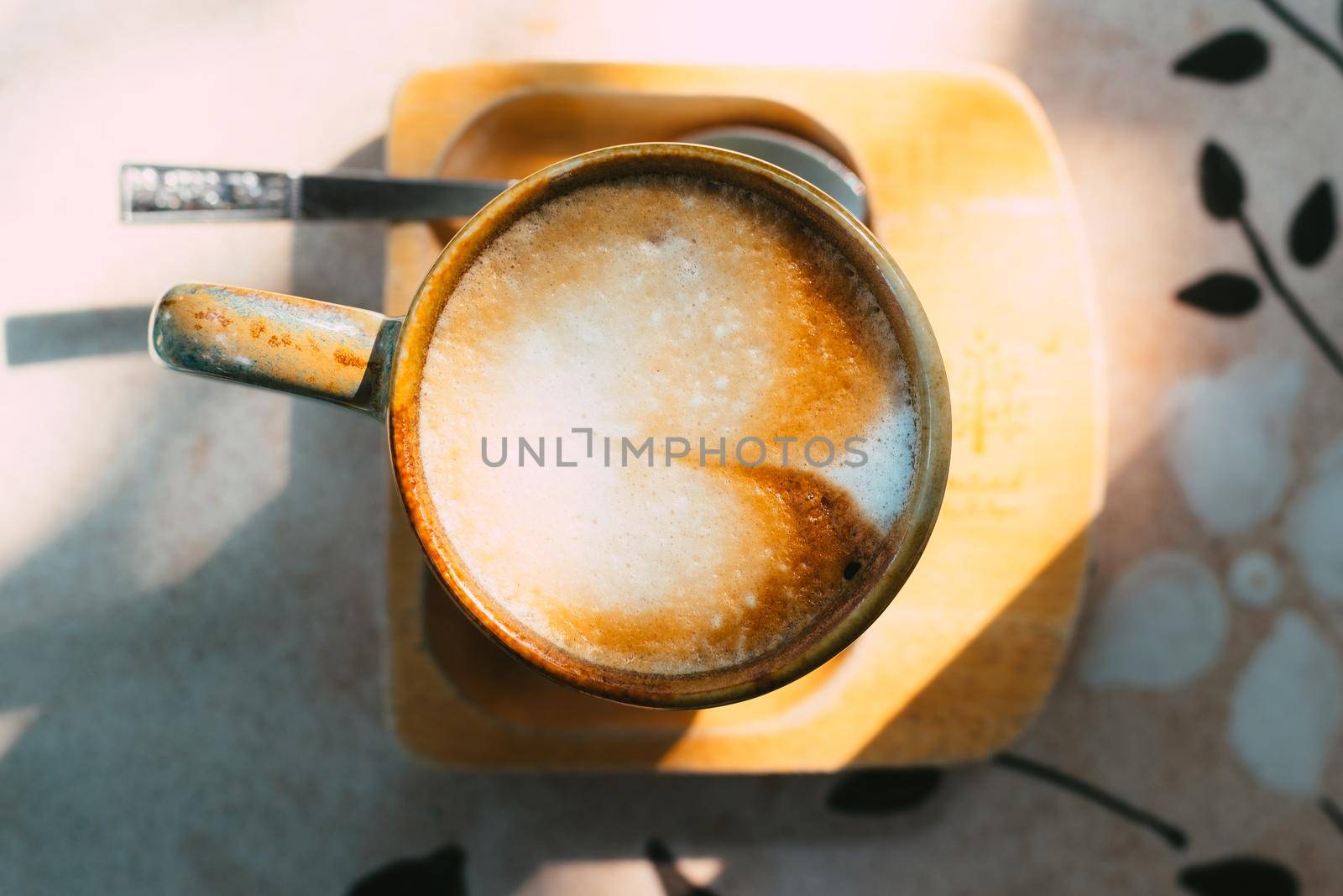 Cup of coffee latte in green poetry mug on old wooden background in the morning sunlight