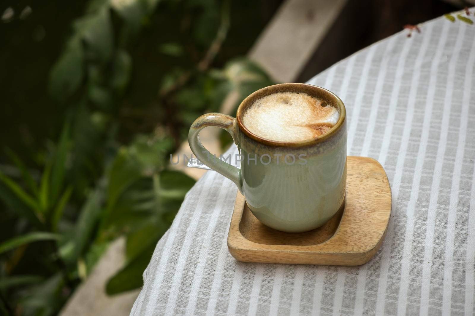 Cup of coffee latte with heart shape on old wooden background in the morning sunlight