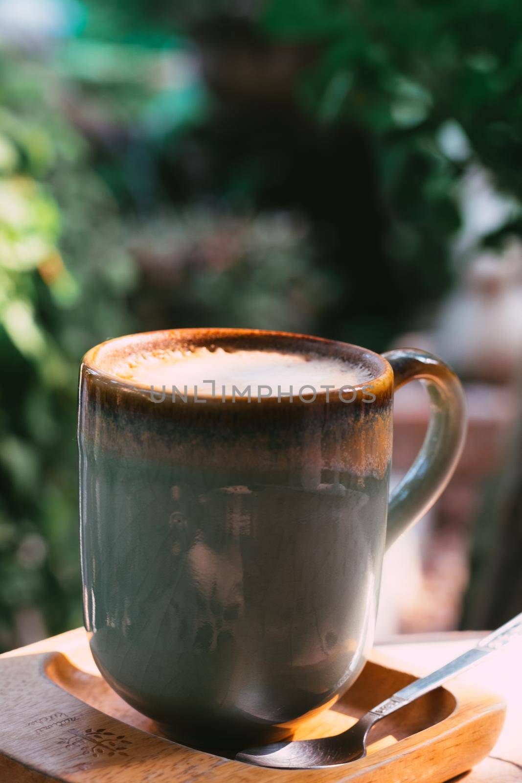 Cup of coffee latte in green poetry mug on old wooden background in the morning sunlight