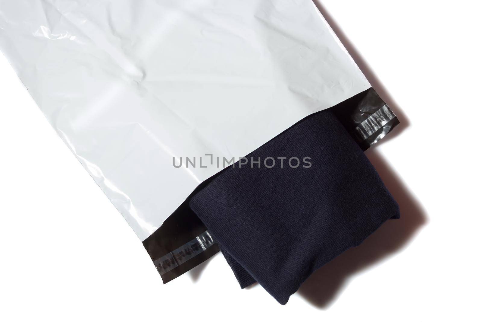 Blue jumper in white plastic mailing bag on white background