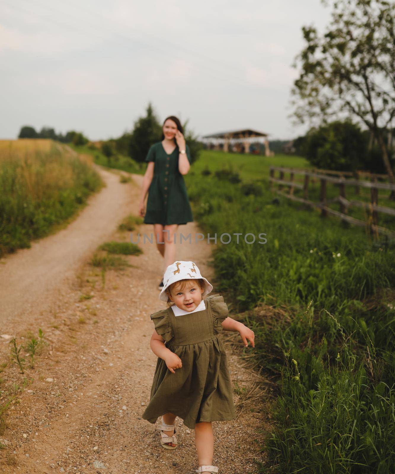 Happy family, active mother with little child, adorable toddler girl. Happy mom is playing with a toddler girl outdoors in summer by paralisart