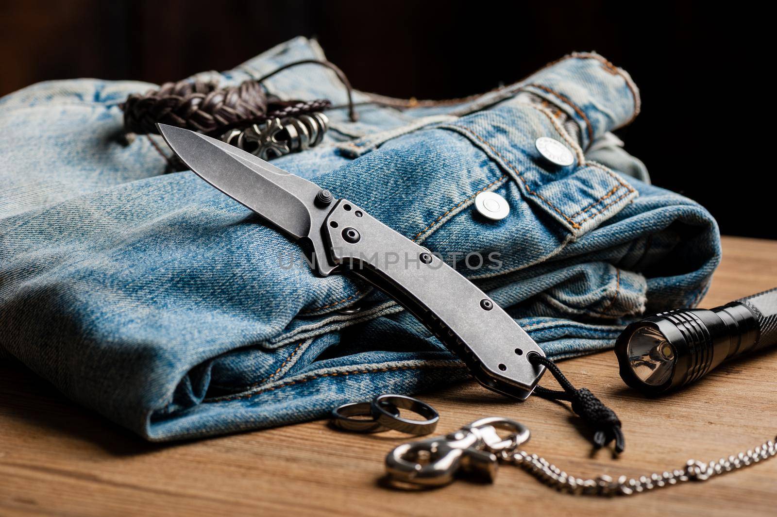 folding knife and jeans. closeup stainless steel pocketknife with blackwash finish on blade and handle.