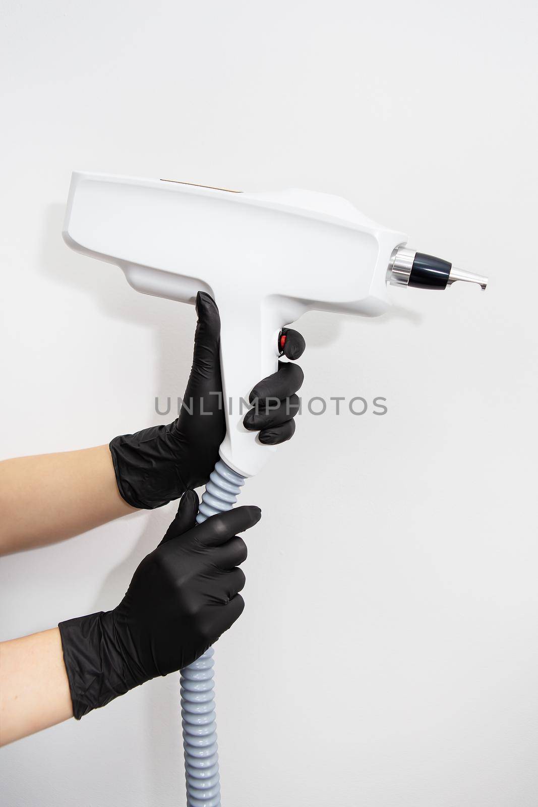 The master of laser hair removal holds a laser hair removal machine in his hands. Removal of hair on all parts of the body. Hair removal machine. by sfinks